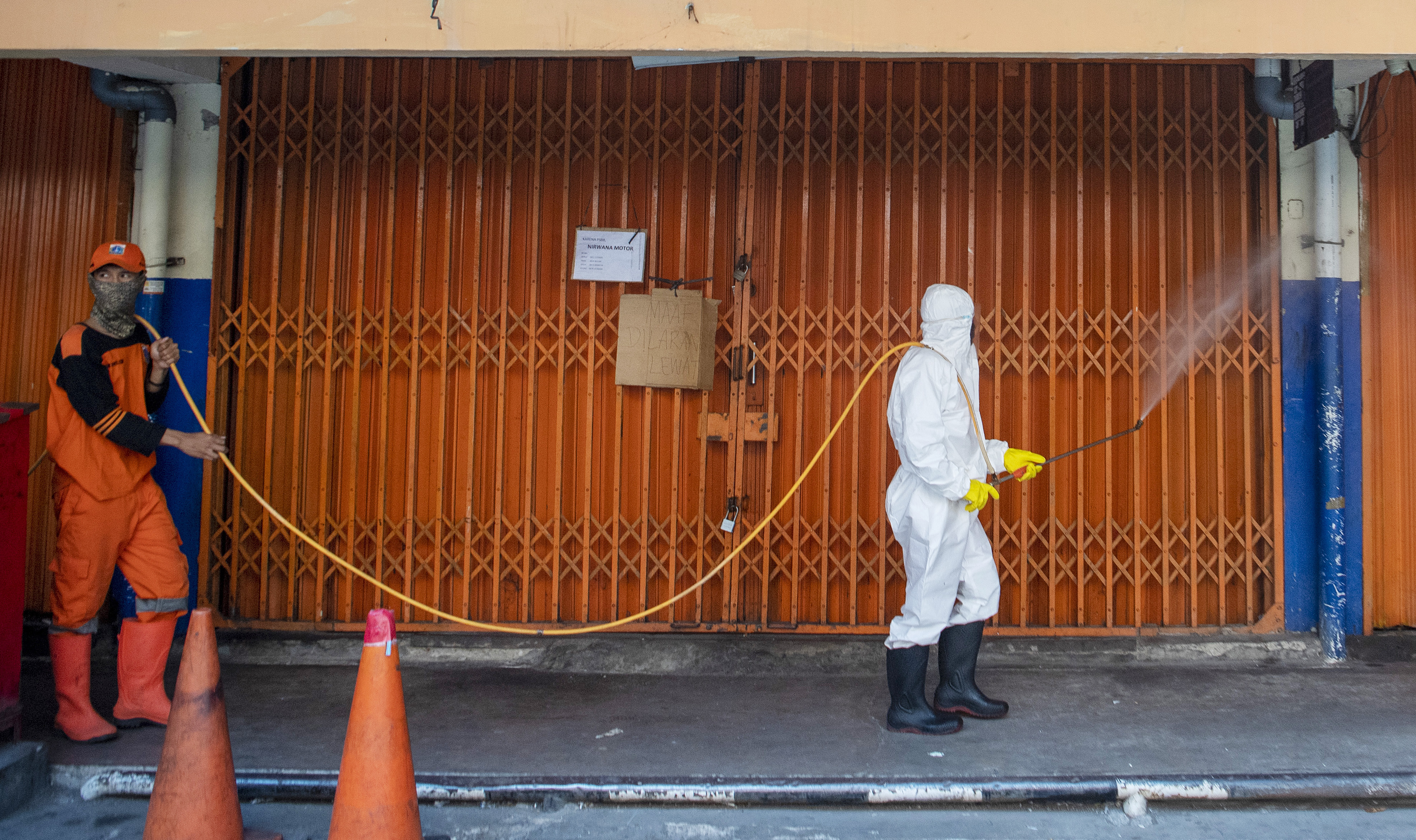 Petugas menyemprotkan cairan disinfektan di area Pasar Asem Reges, Jakarta Barat, Selasa (21/7/2020), karena satu pedagang positif covid-19.