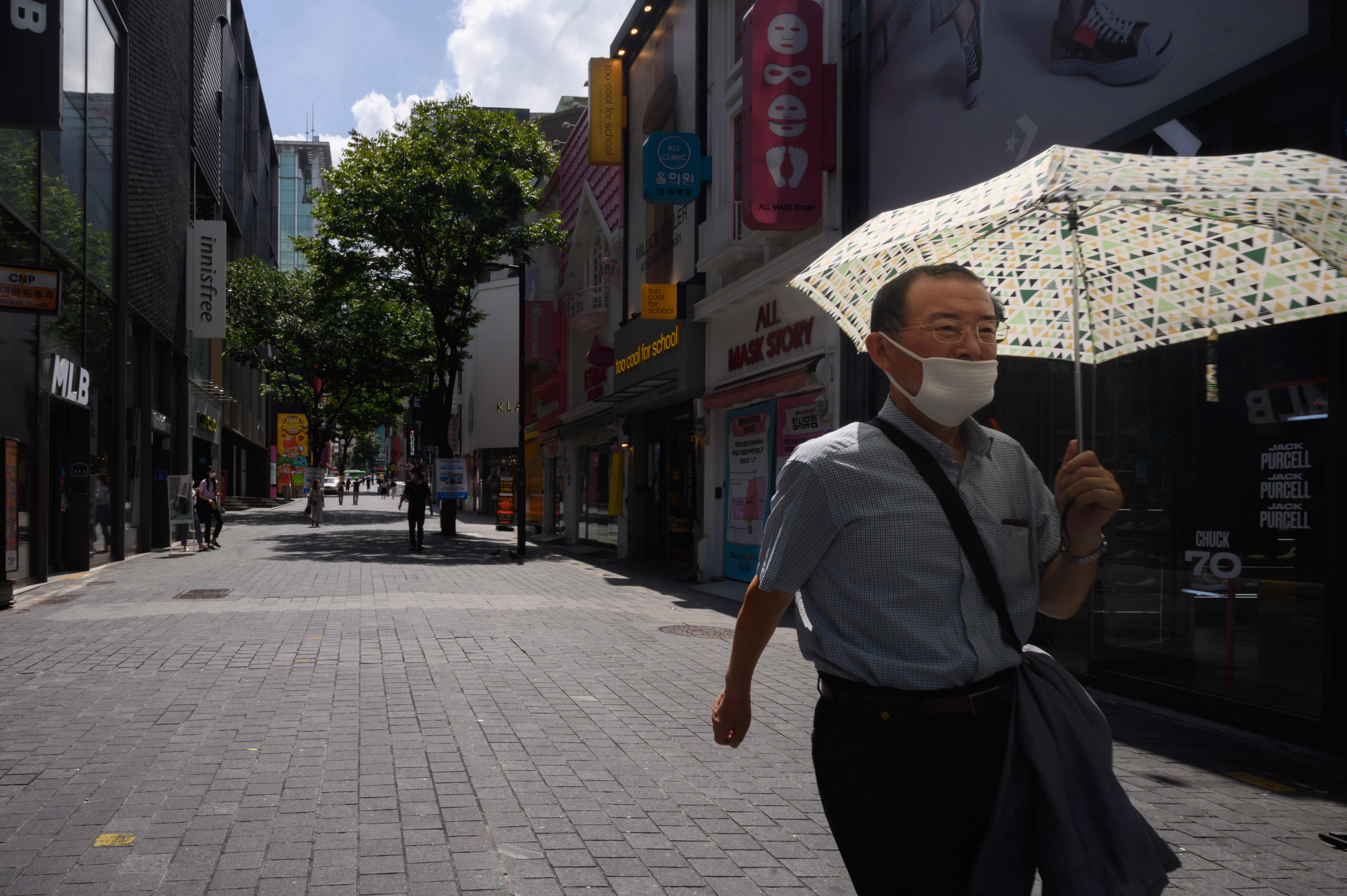 Seorang pria yang mengenakan masker wajah sebagai tindakan perlindungan terhadap virus corona COVID-19 berjalan di  Myeongdong, Seoul 