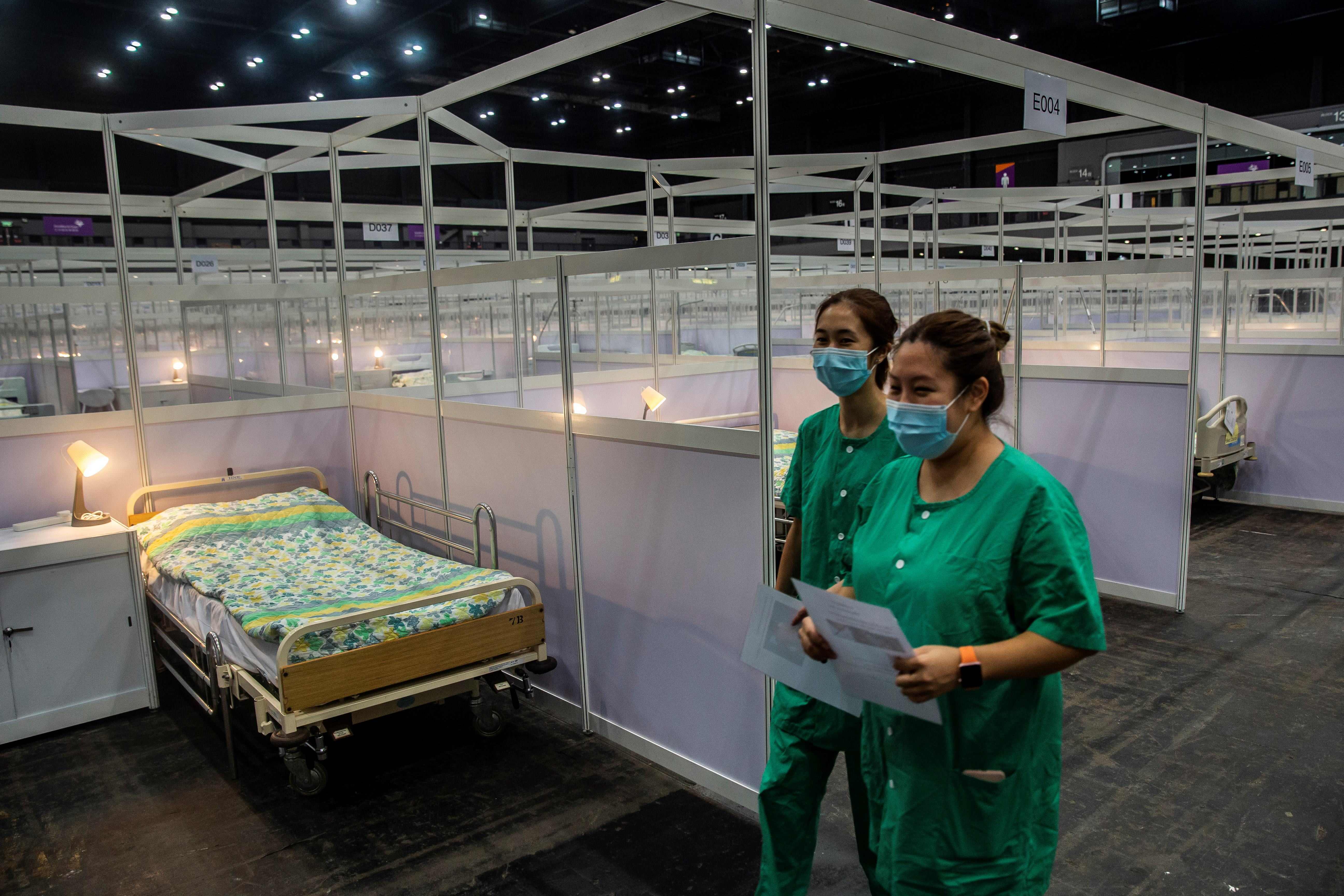 Pekerja medis berjalan melewati barisan tempat tidur di rumah sakit lapangan sementara di Asia World Expo di Hong Kong, Sabtu (1/8).
