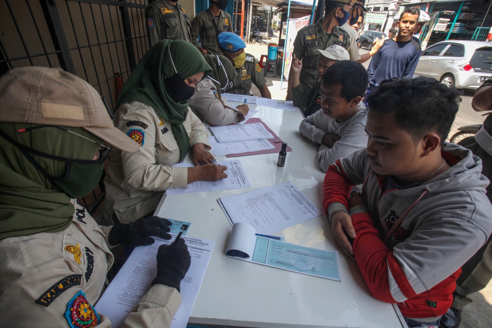 Petugas Satpol PP menilang warga yang tidak menggunakan masker saat razia di Jalan Raya Karadenan, Bogor, Jawa Barat, Kamis (27/8).