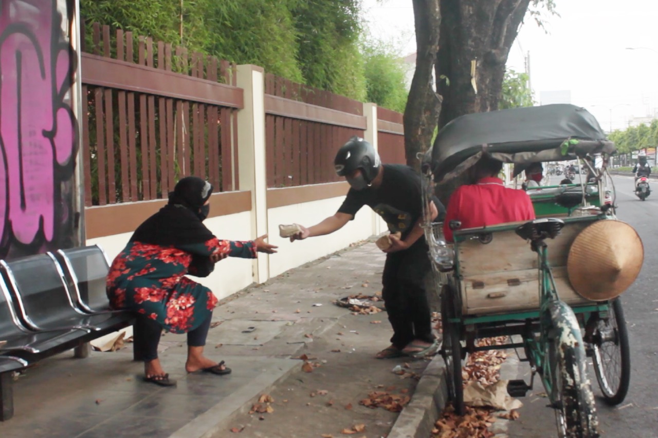 Christian Apri Wijaya, Apri, anggota Mukti, membagikan nasi bungkus kepada tukang becak dan pekerja informal yang dijumpai di Jalan Gejayan.