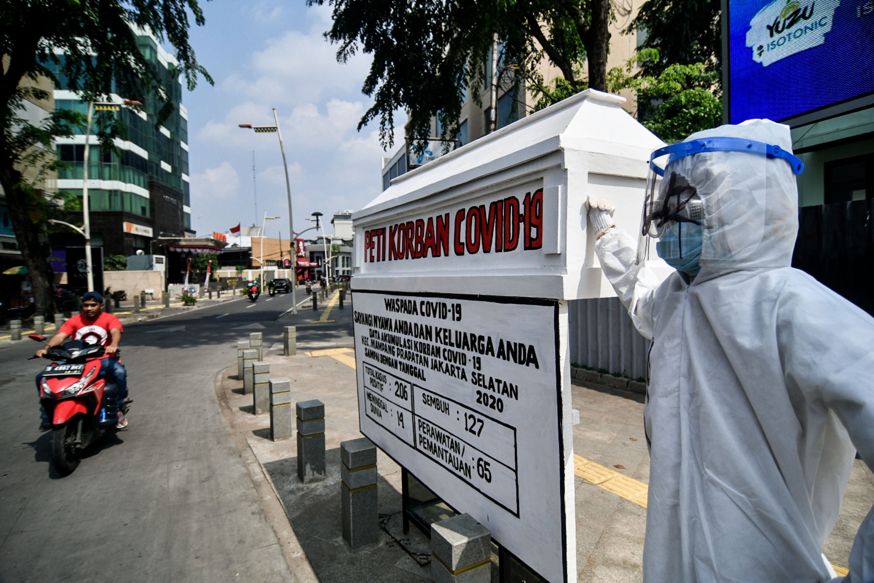 Pengendara melintas di depan seni instalasi tenaga medis memegang peti jenazah korban covid-19 di Jakarta, Sabtu, (16/8). 