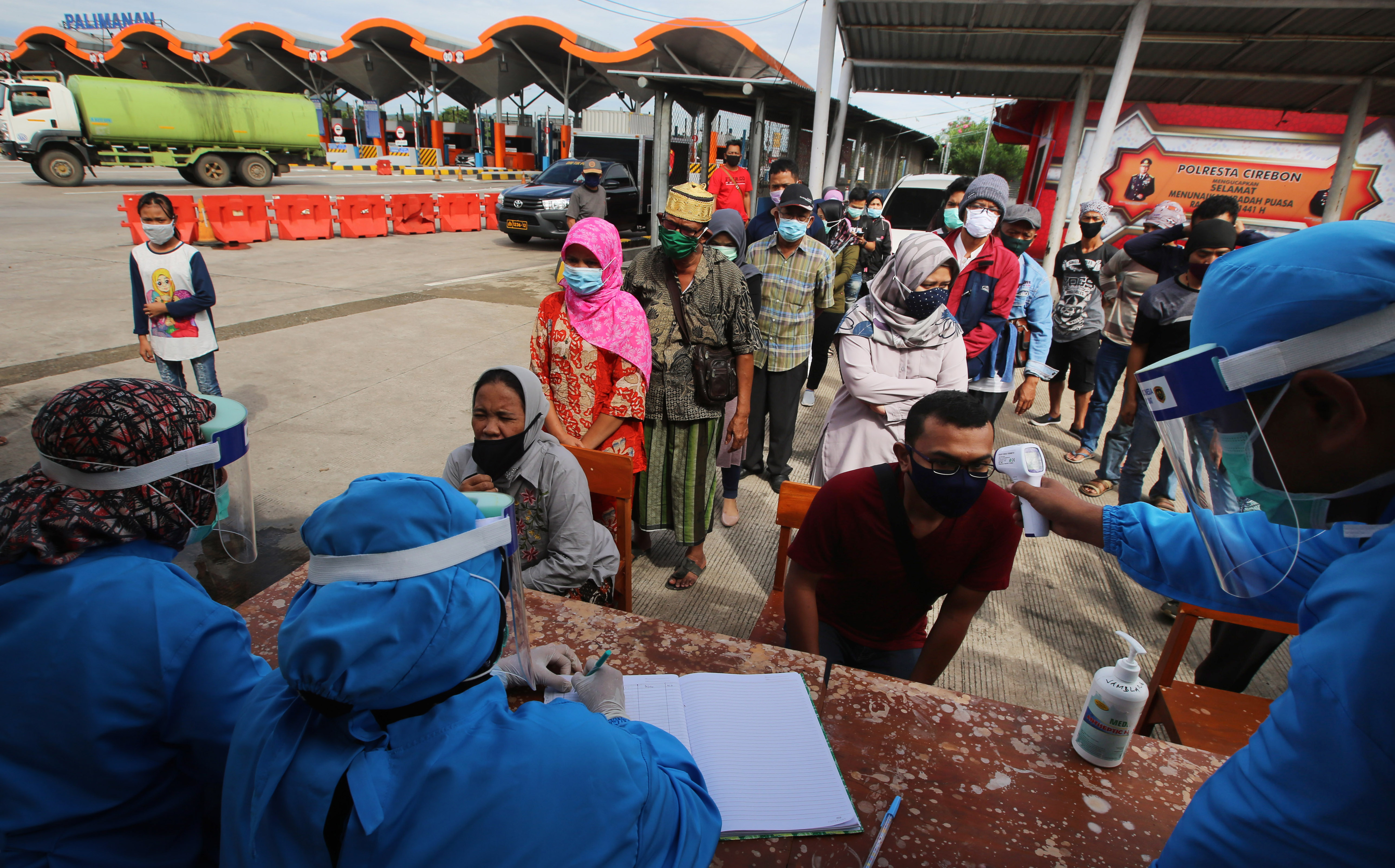 Petugas memeriksa suhu tubuh warga yang diduga pemudik di check point pintu keluar Gerbang Tol Palimanan Utama, Cirebon, Kamis (21/5).