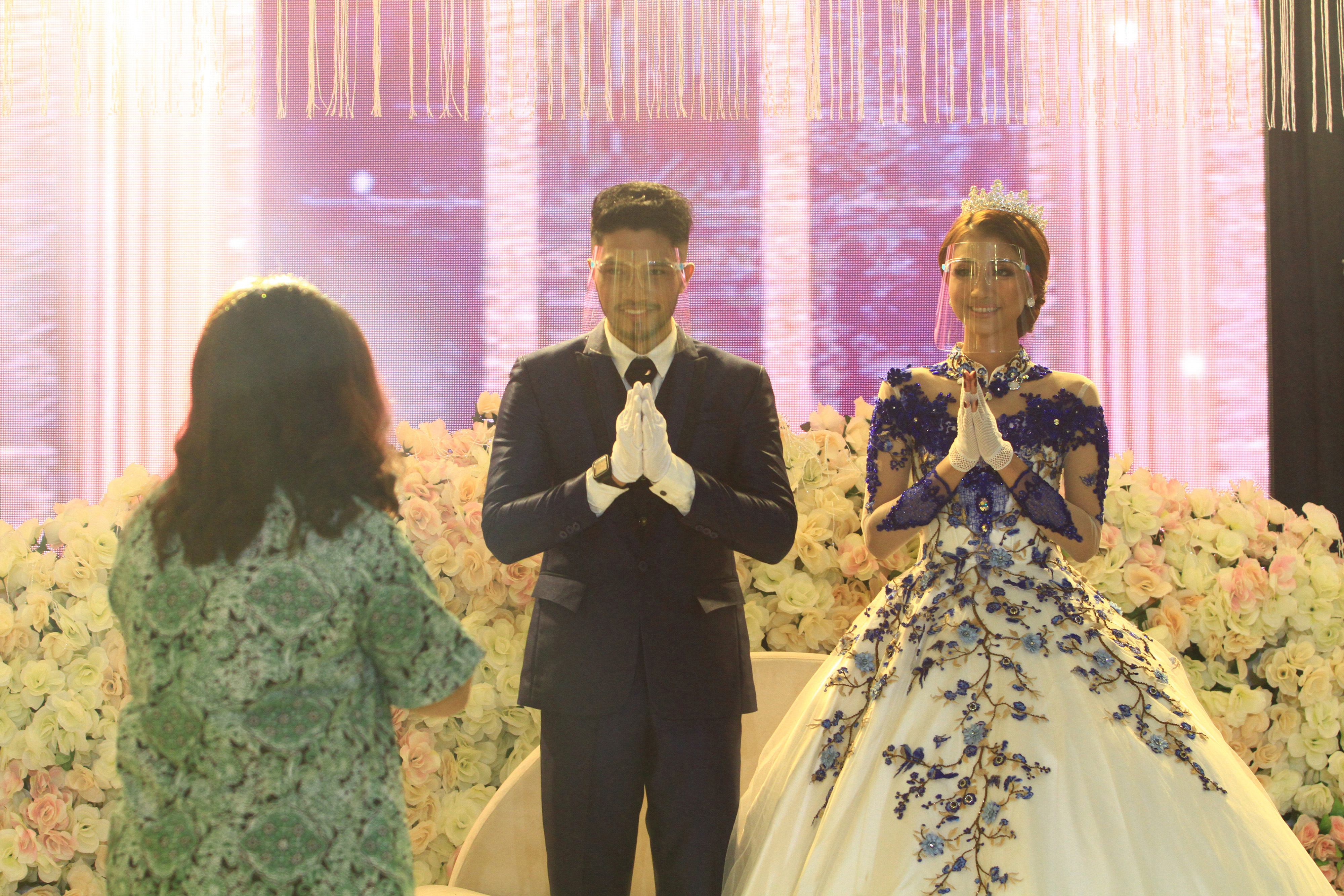 Pasangan pengantin mengenakan alat pelindung wajah untuk mencegah penularan covid-19.