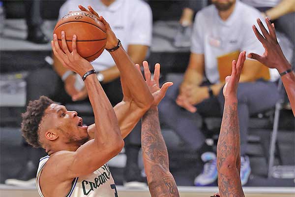 Pemain Milwaukee Bucks Giannis Antetokounmpo (kiri) hendak melempar bola ke keranjang saat dihadang pemain Houston Rockets PJ Tucker