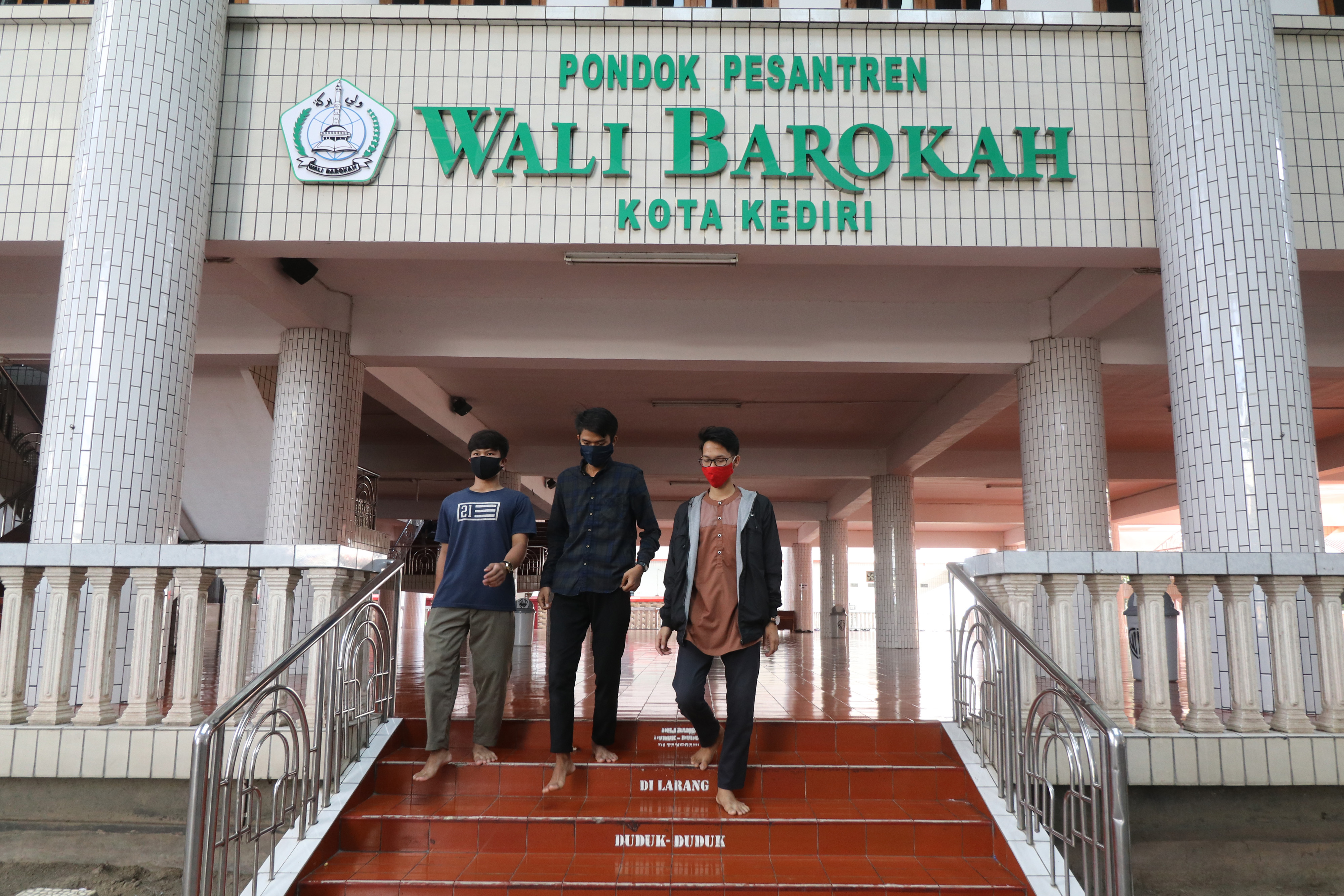 NORMAL BARU: Tiga santri mengenakan masker menuruni tangga di gedung utama Ponpes LDII, Wali Barokah Kediri, Jatim 