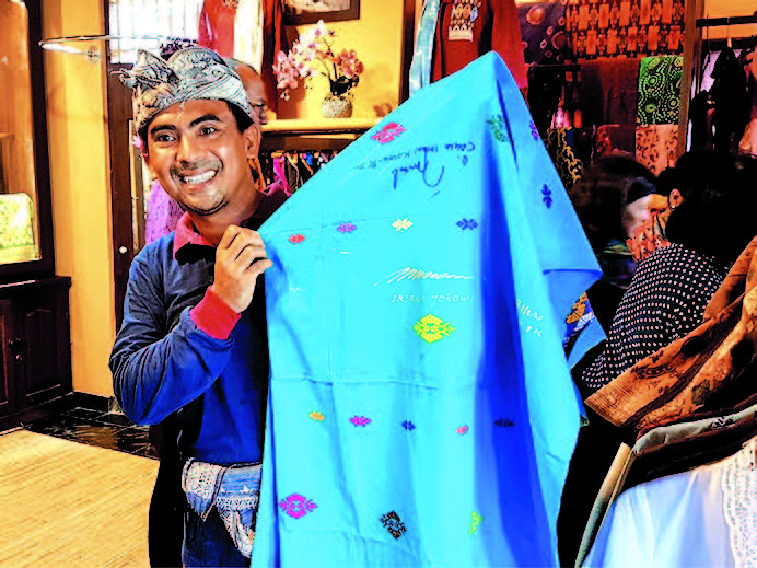 Ilustrasi: I Ketut Widiadnyana menunjukkan selembar songket yang dipenuhi goresan tanda tangan tokoh nasional.