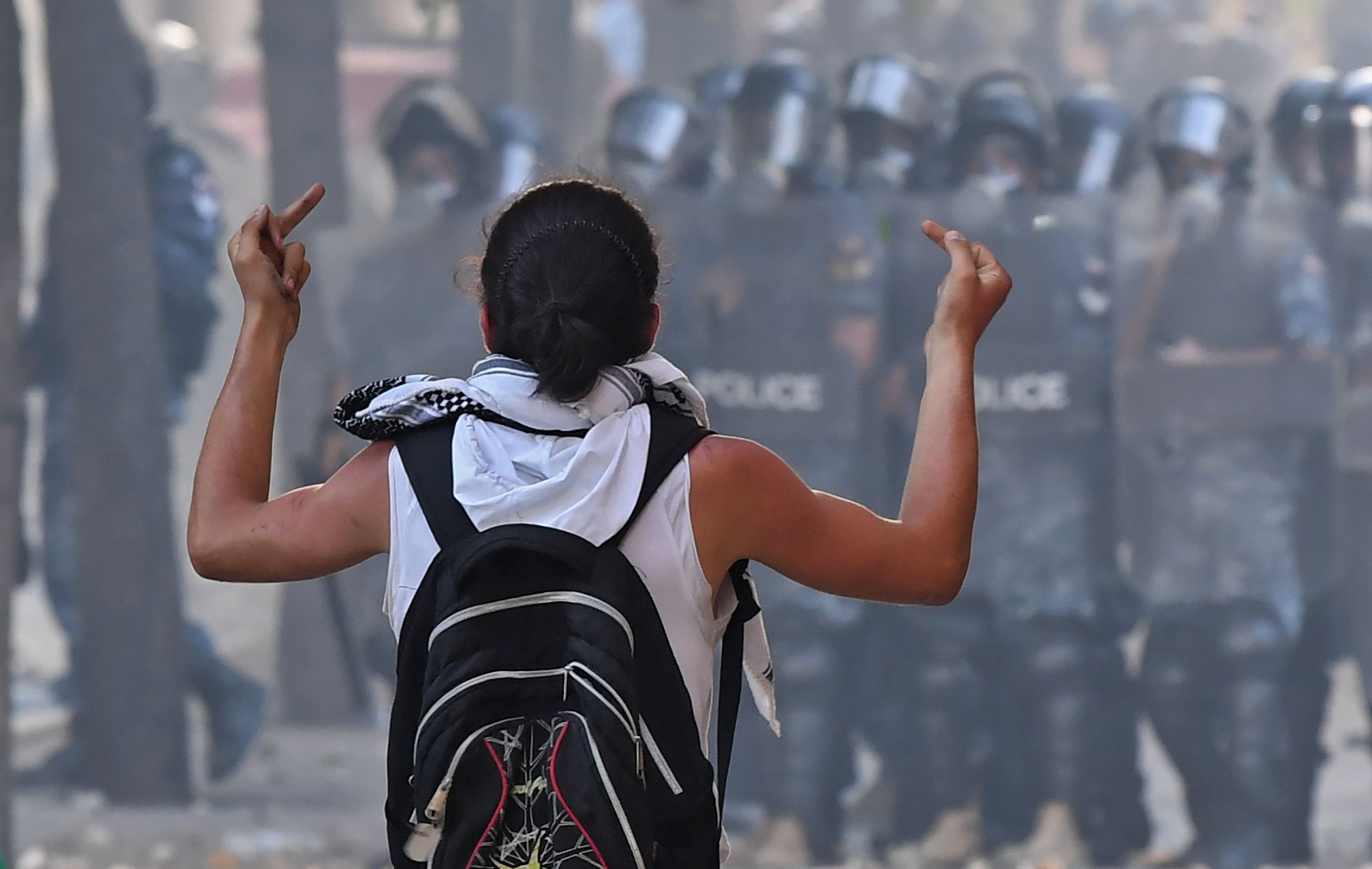 Seorang pengunjuk rasa memberikan tanda jari tengah pada pasukan keamanan di Beirut