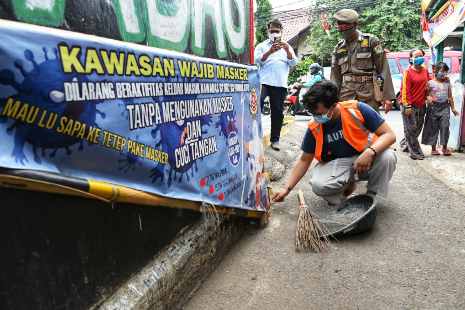  Petugas Satpol PP memberi sanksi menyapu jalan kepada warga yang tidak mengenakan masker di Pondok Kopi, Jakarta Timur, Rabu (13/8).