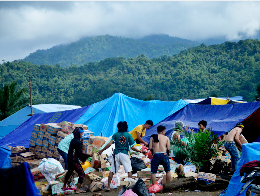 Warga korban banjir bandang bersama relawan mengatur bantuan logistik di pengungsian kawasan perbukitan di Desa Meli, Kecamatan Baebunta, Ka