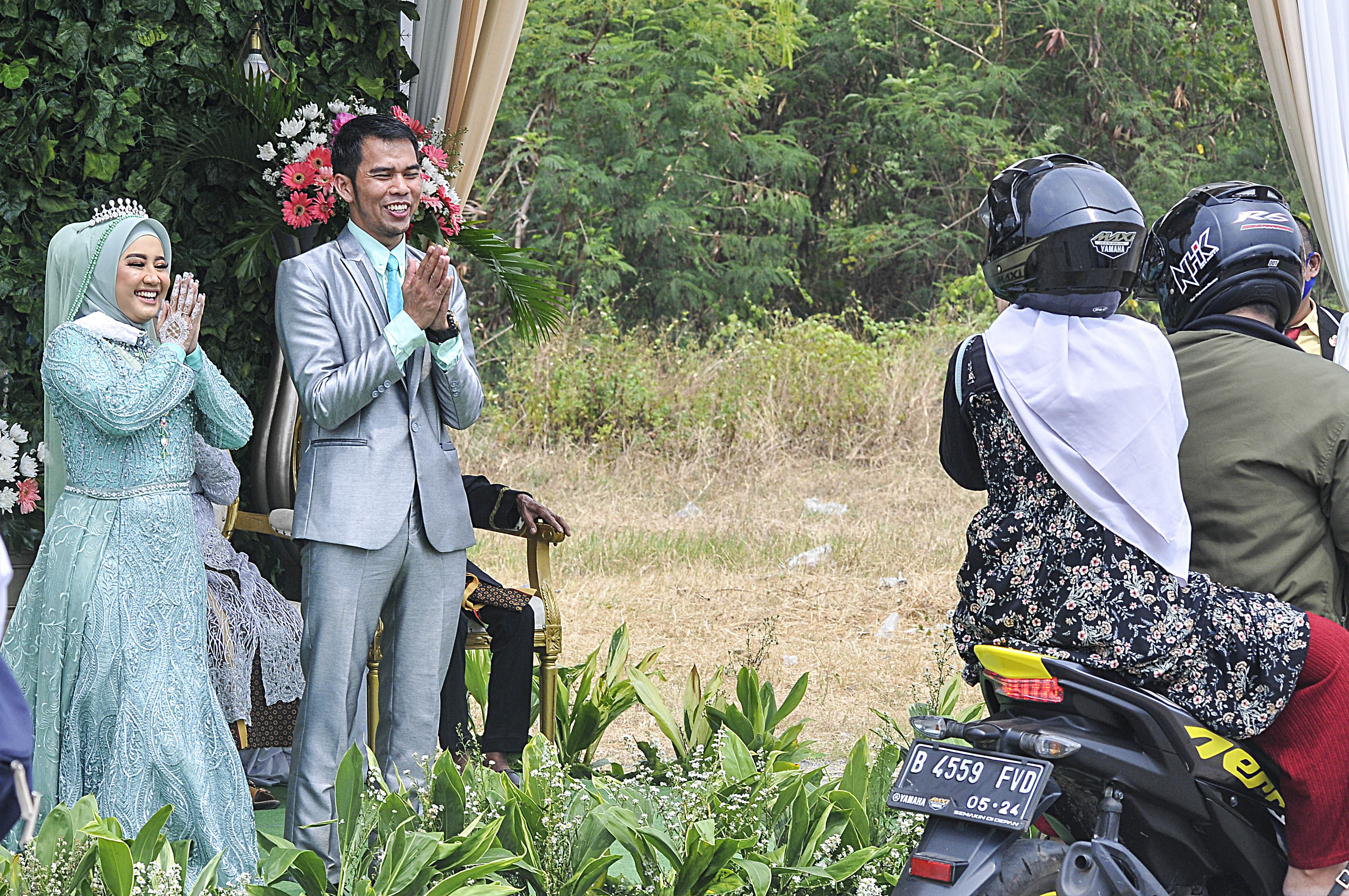 Pasangan mempelai saat menyapa tamu pada acara resepsi pernikahan secara 'drive thru' di Bekasi