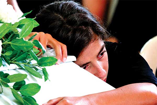 Carole Helou memeluk peti mati saudara perempuannya, Nicole, yang tewas dalam ledakan besar di Beirut