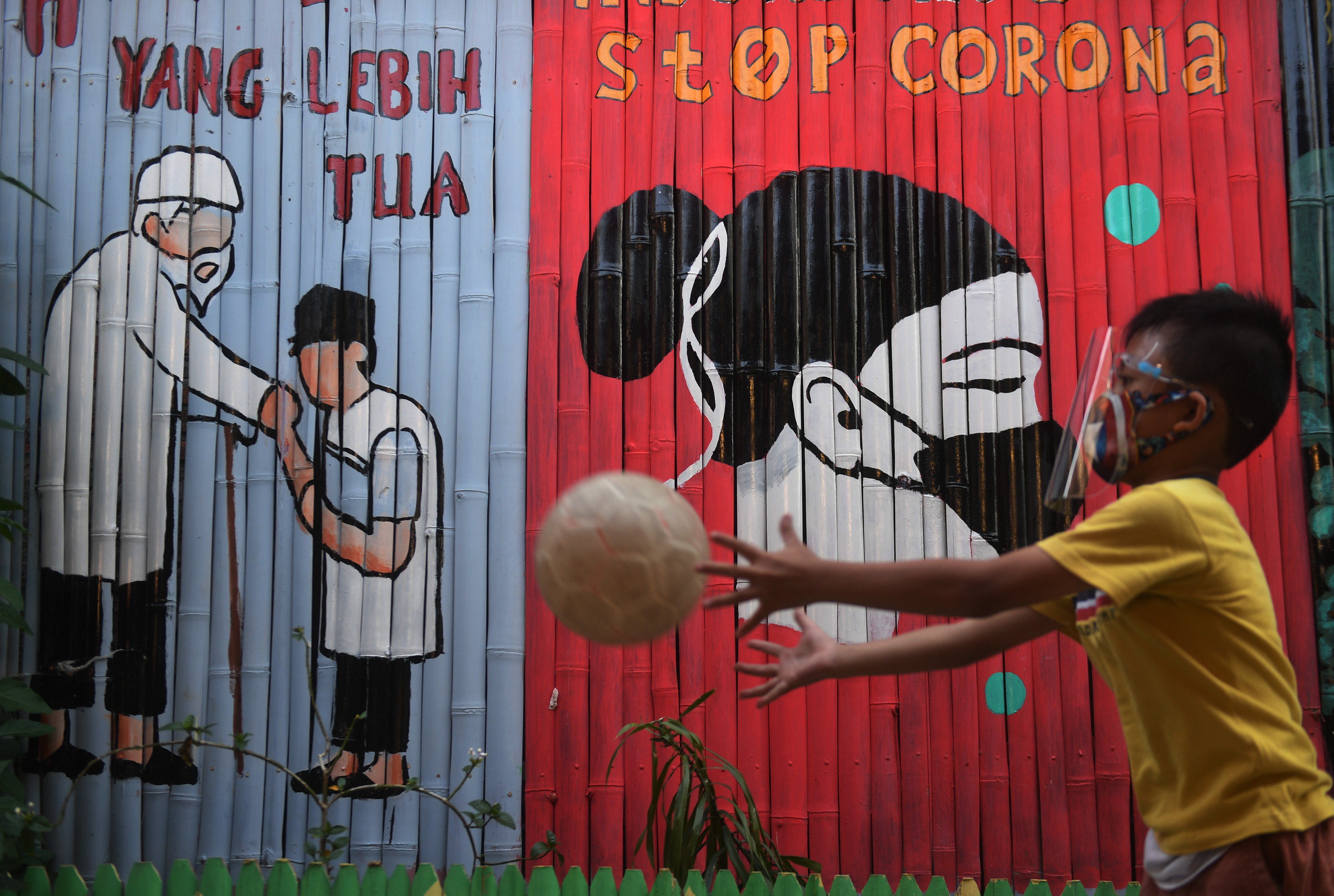 Seorang anak bermain di depan mural bertema COVID-19 di Jakarta (27/7/2020)