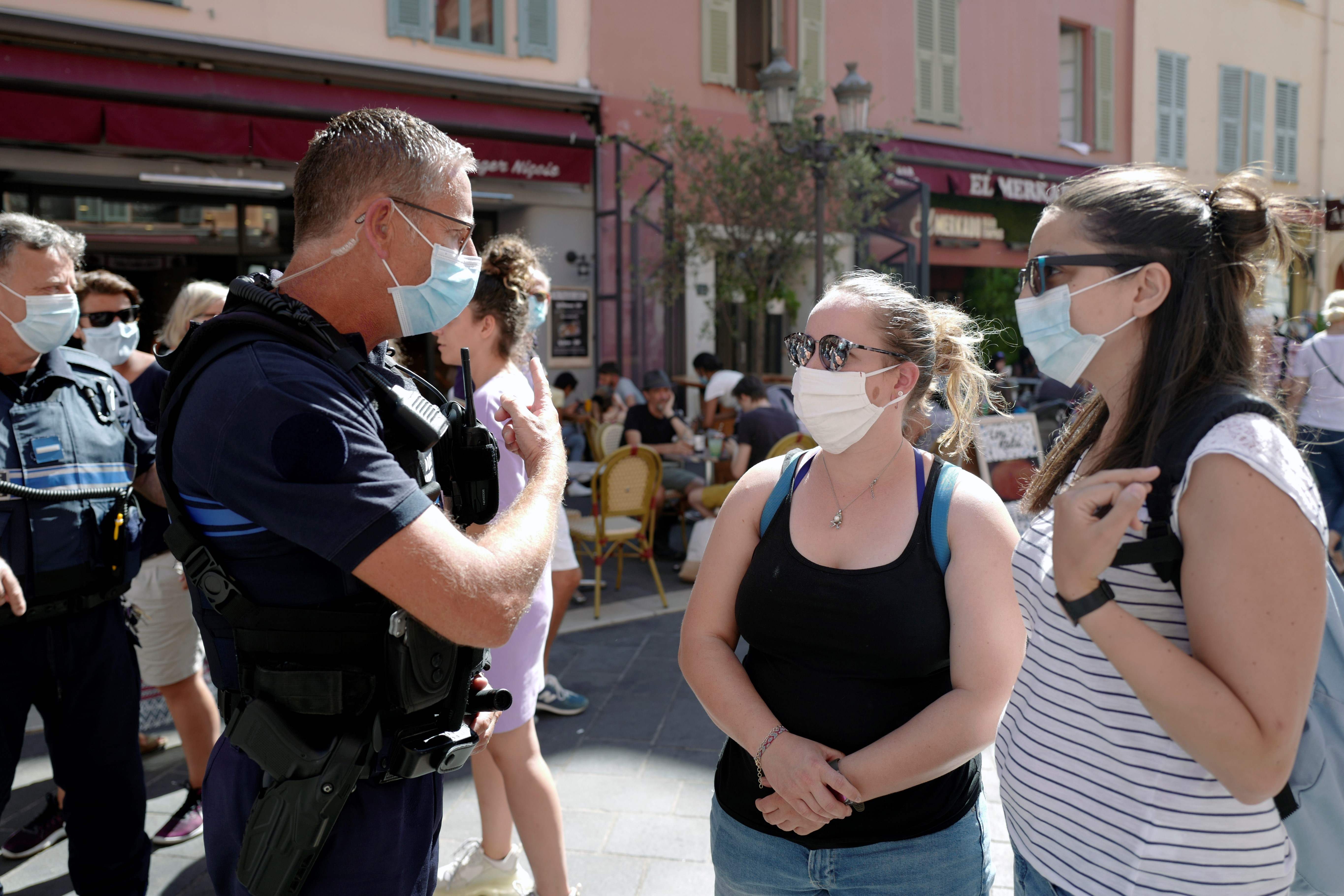 Polisi berbincang dengan warga yang mengenakan masker di Nice, Prancis.
