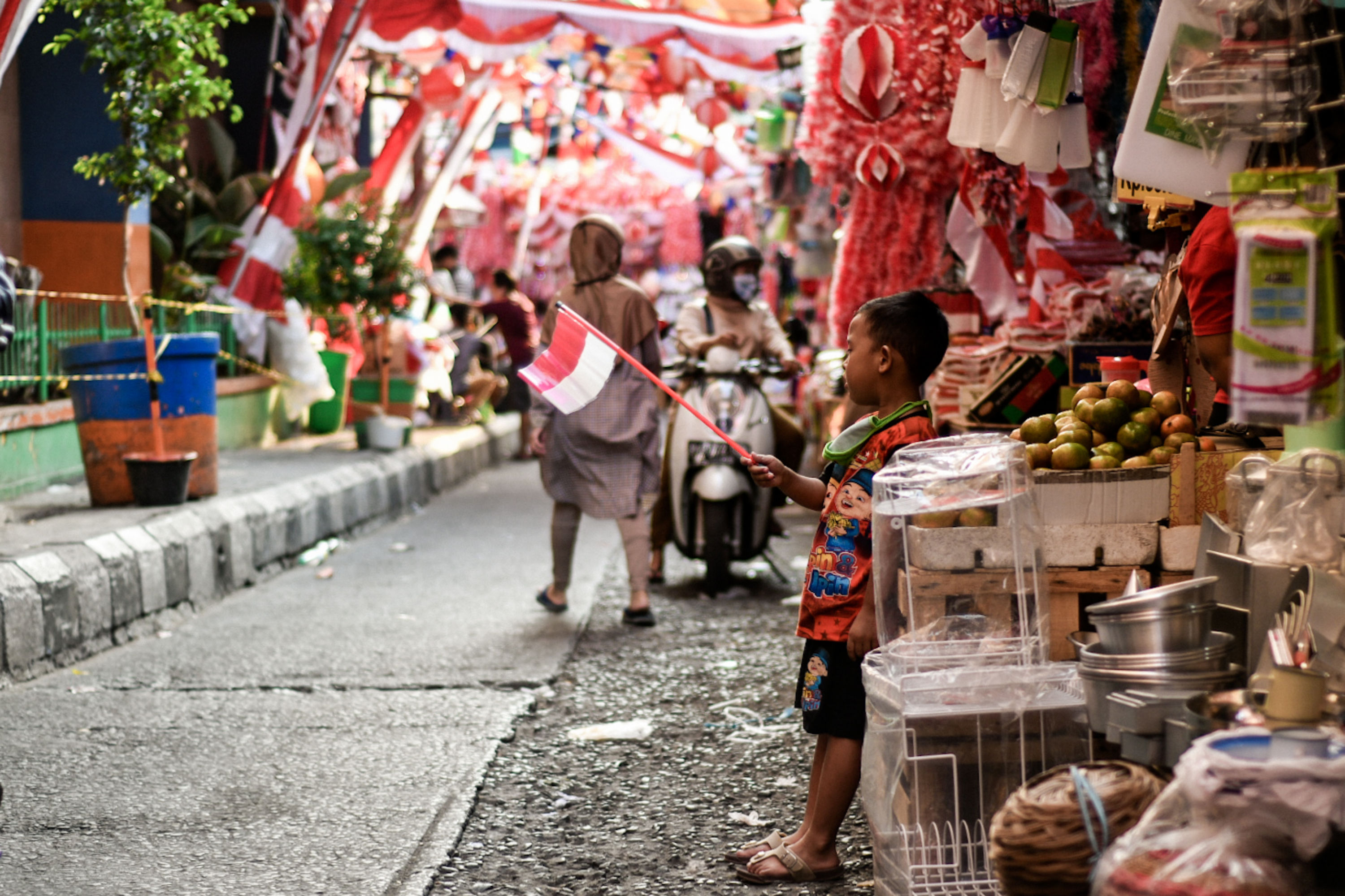 Seorang anak mengibarkan miniatur bendera Indonesia di Pasar Jatinegara, Jakarta, Senin (3/8).