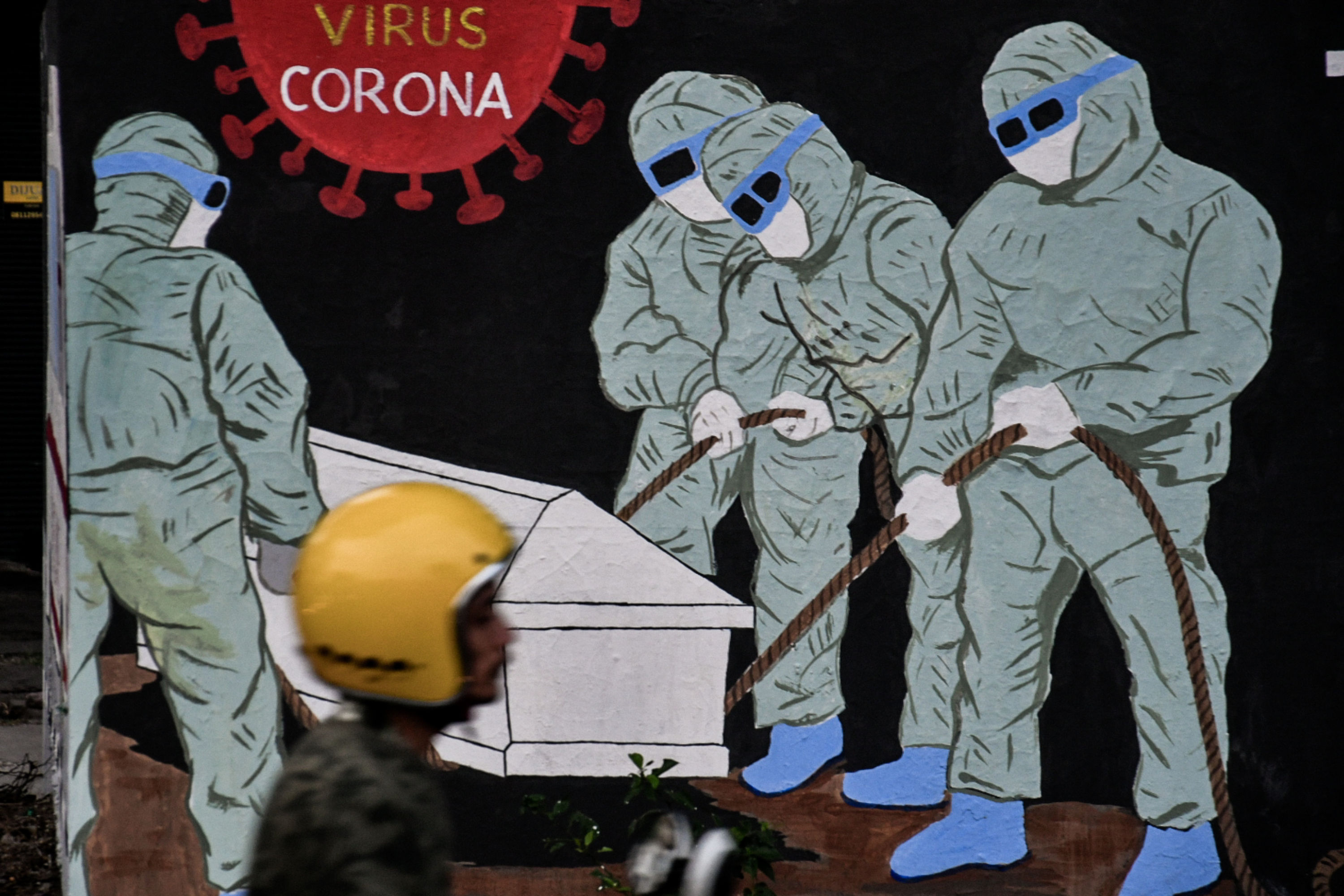 Pengendara melintas di depan mural bertema covid-19 di Tebet, Jakarta, Selasa (11/8/2020)