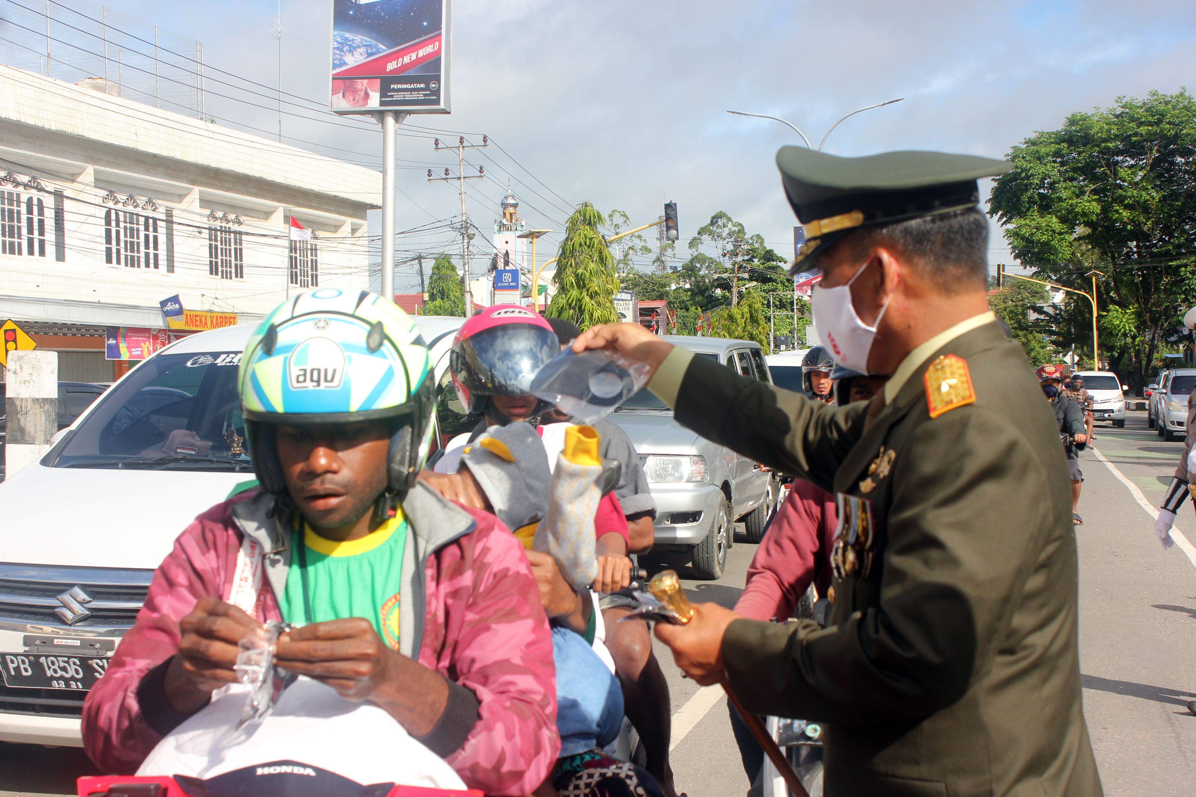 Danrem 181 Praja Vira Tama, Brigjen TNI Yulius Selvanus (kanan) membagikan masker kepada pengendara motor di Jalan Ahmad Yani, Kota Sorong.