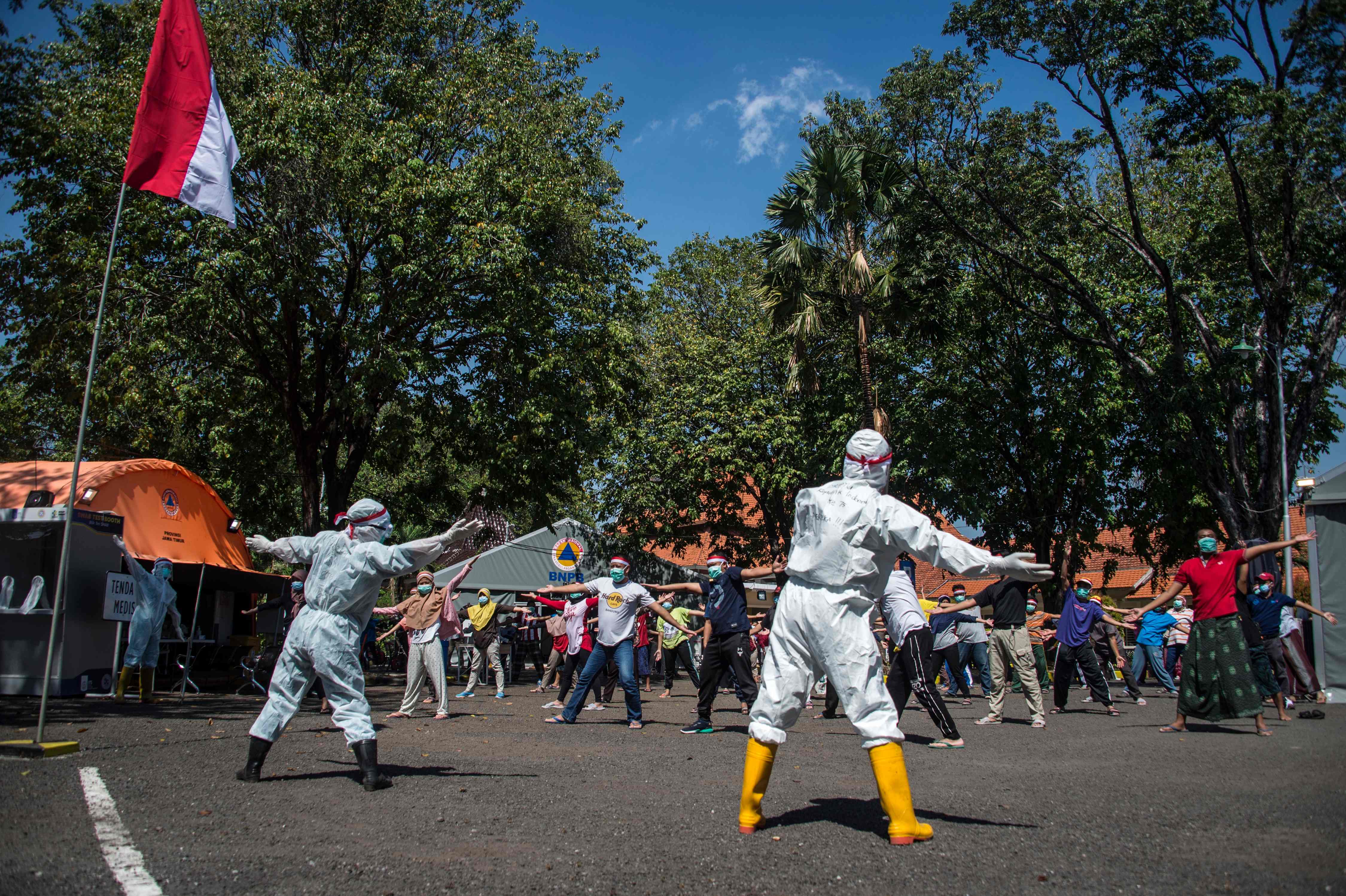 Petugas mengenakan APD memimpin senam pagi bagi pasien covid-19 bergejala ringan di sebuah rumah sakit darurat di Surabaya.