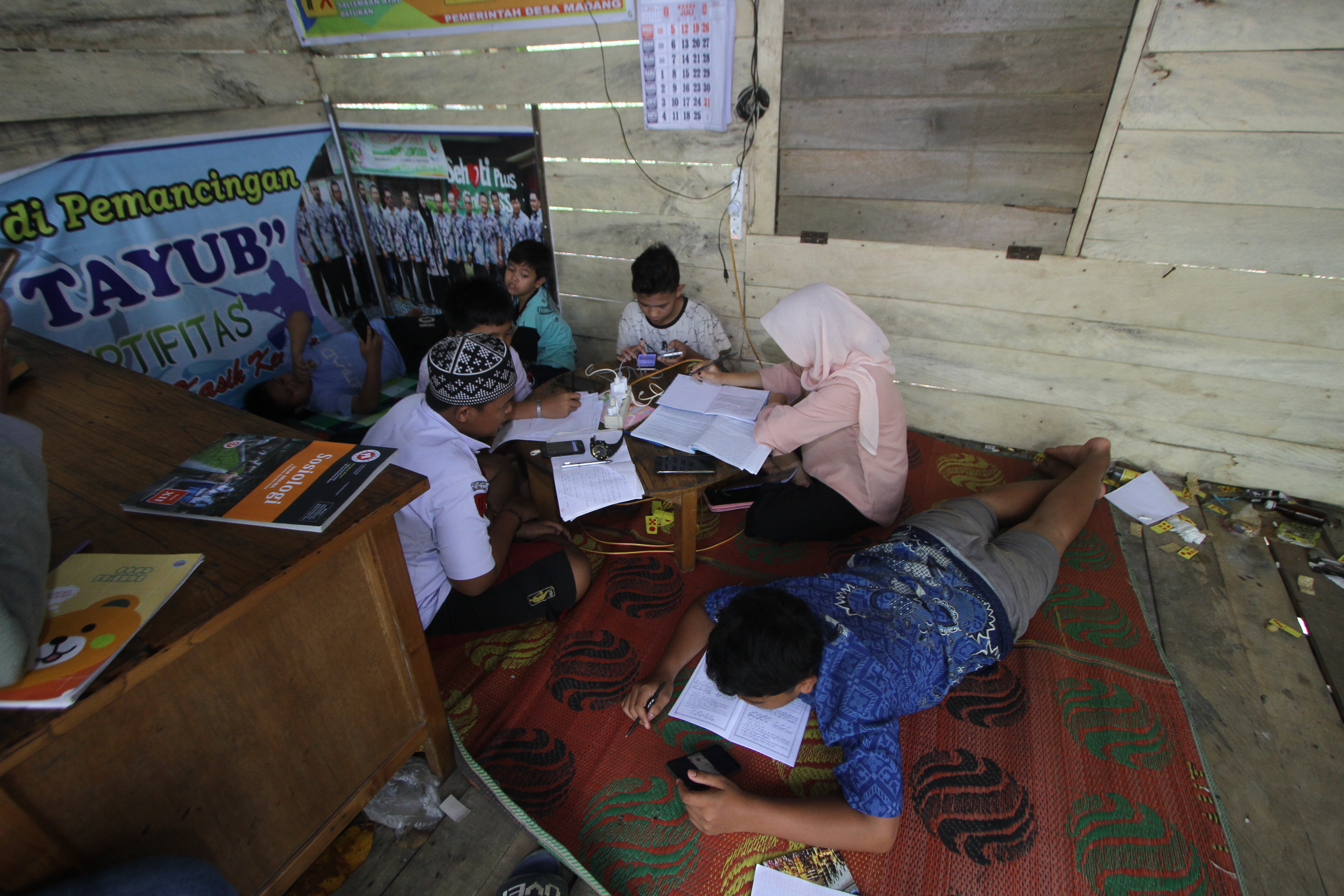Anak-anak di Desa Madang pedalaman Kalimantan Selatan memanfaatkan internet dari pos ronda untuk belajar daring.