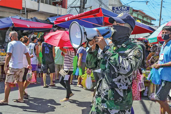 KEMBALI TERAPKAN LOCKDOWN: Anggota Polisi Nasional Filipina menggunakan pelantang untuk mengingatkan pembeli agar mempraktikkan jarak sosial
