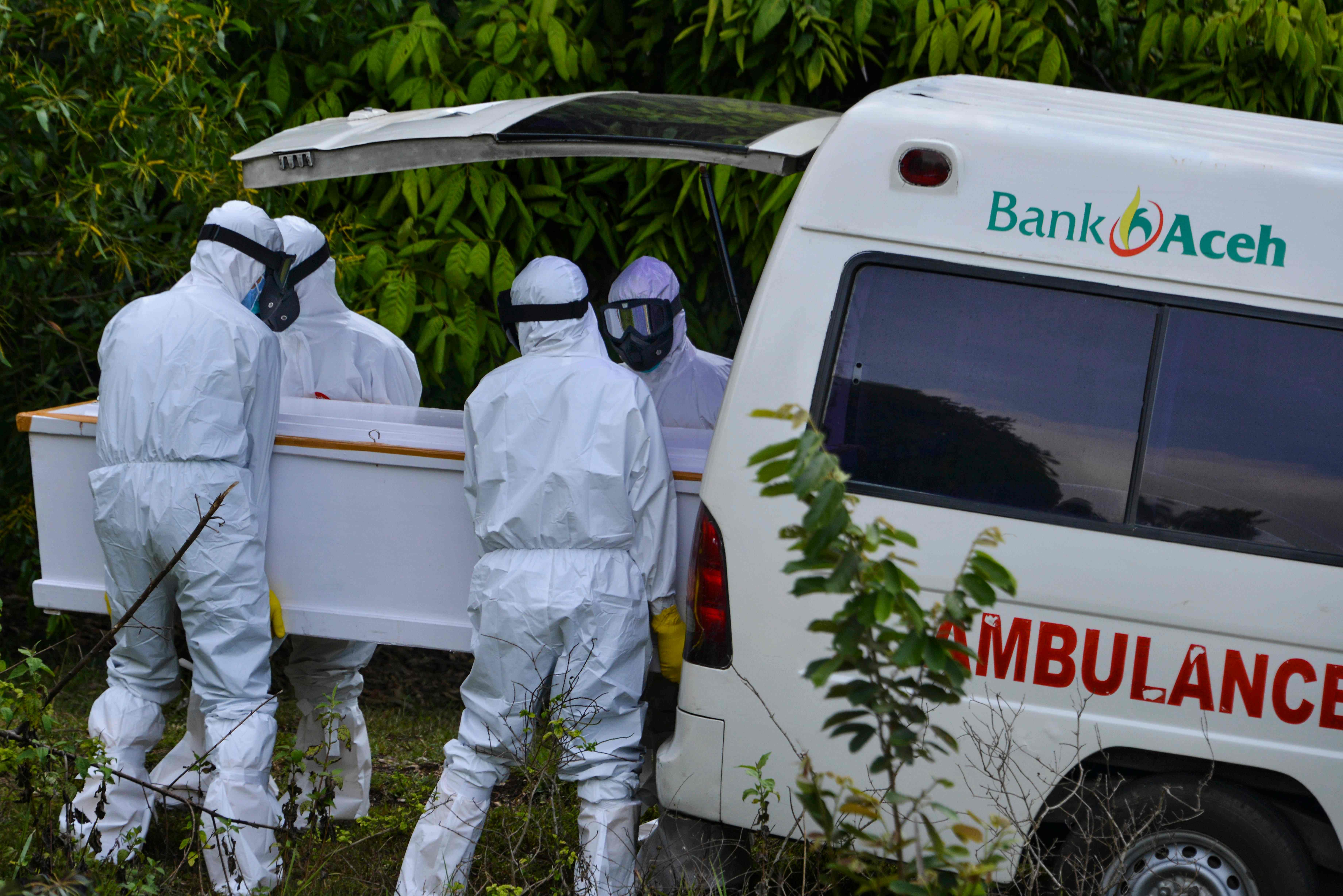 Petugas mengenakan APD membawa peti jenazah pasien covid-19 keluar dari ambulans di sebuah TPU di Banda Aceh.
