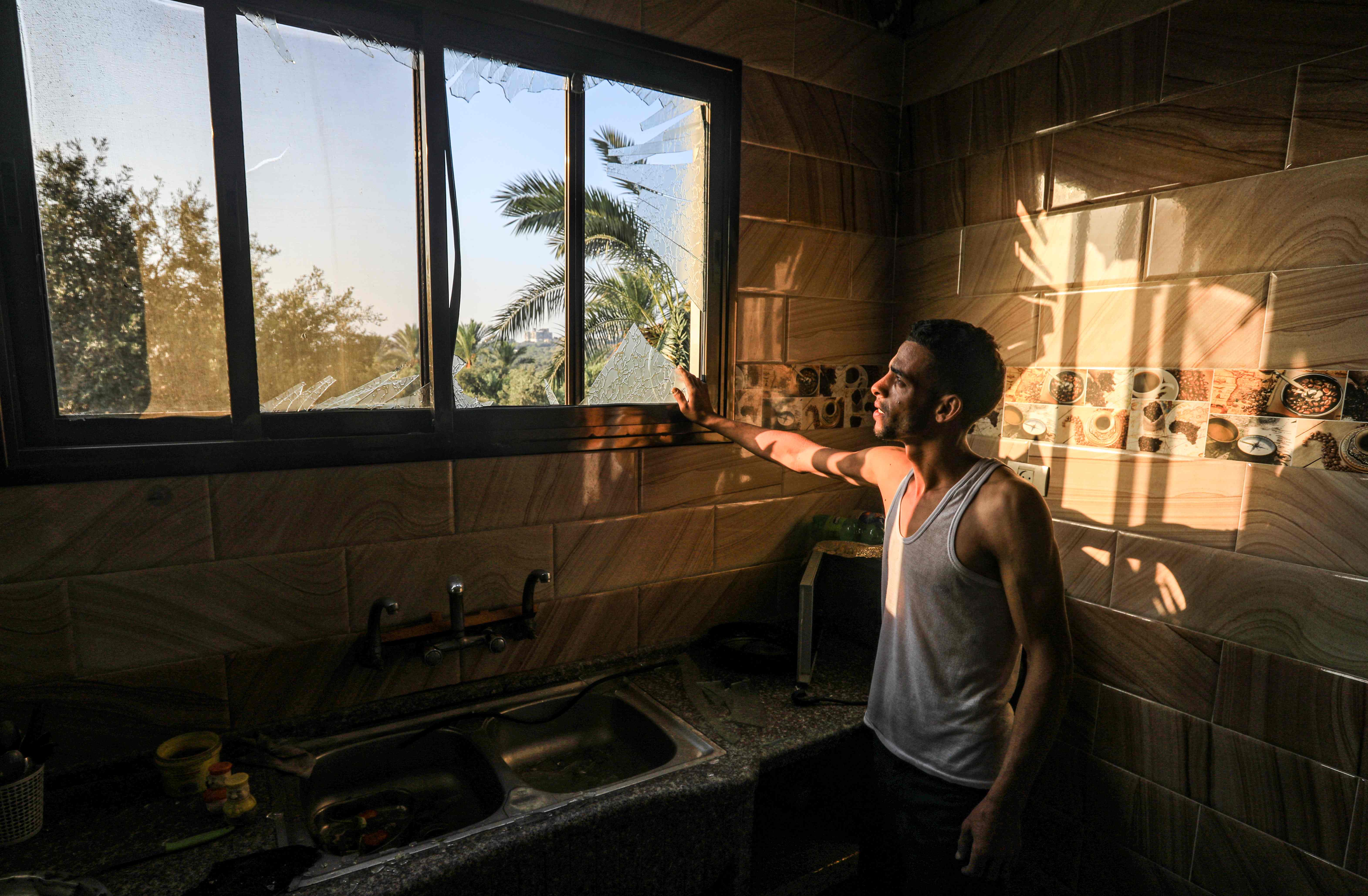 Warga menunjukkan jendela kaca yang pecah akibat serangan udara Isreael di selatan al Bureij, kamp pengungsi Palestina di jalur Gaza.