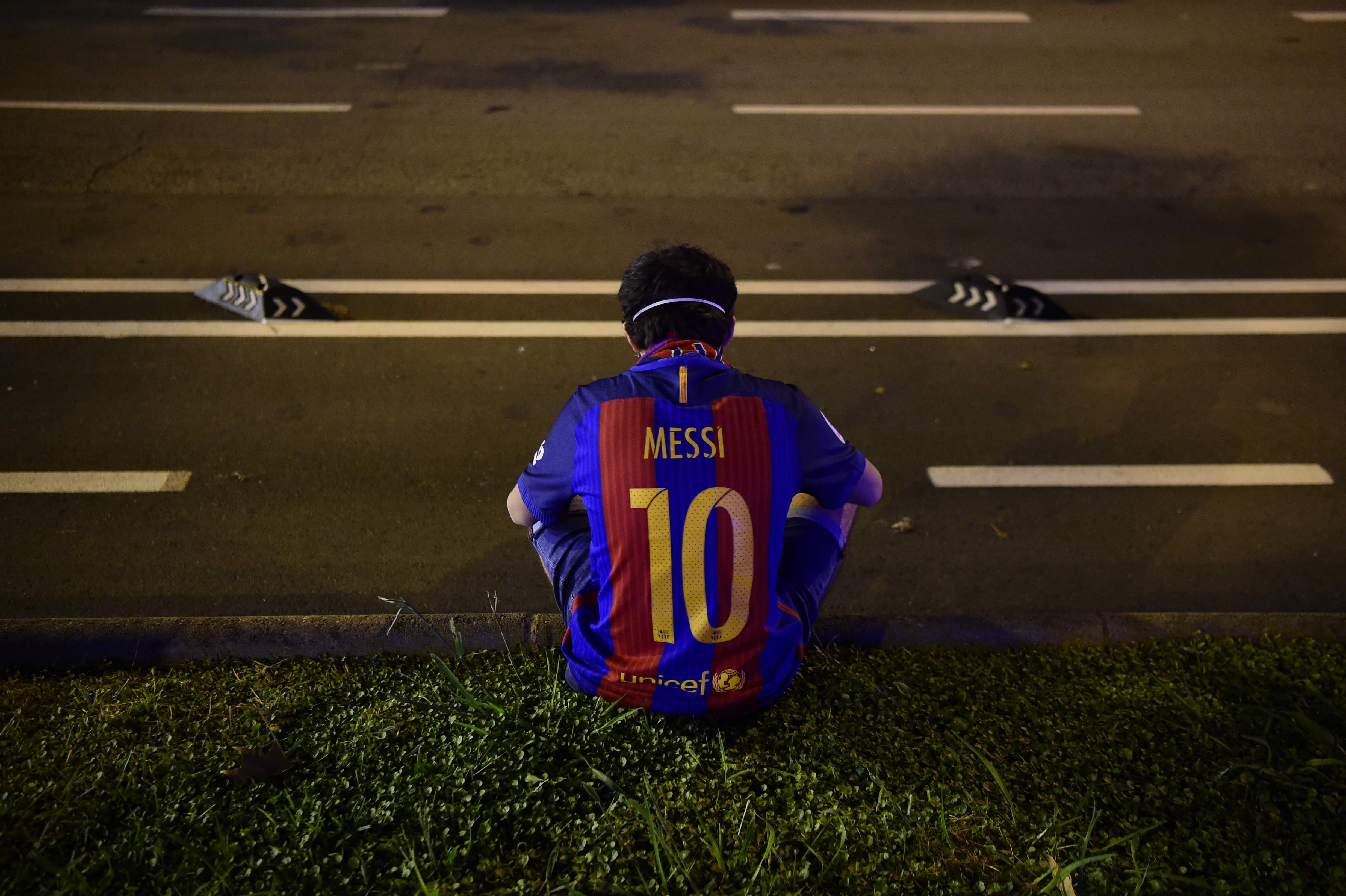 Seorang fan Barcelona duduk di depan Stadion Nou Camp. Fan Barcelona ingin Lionel Messi bertahan di klub Spanyol itu.   