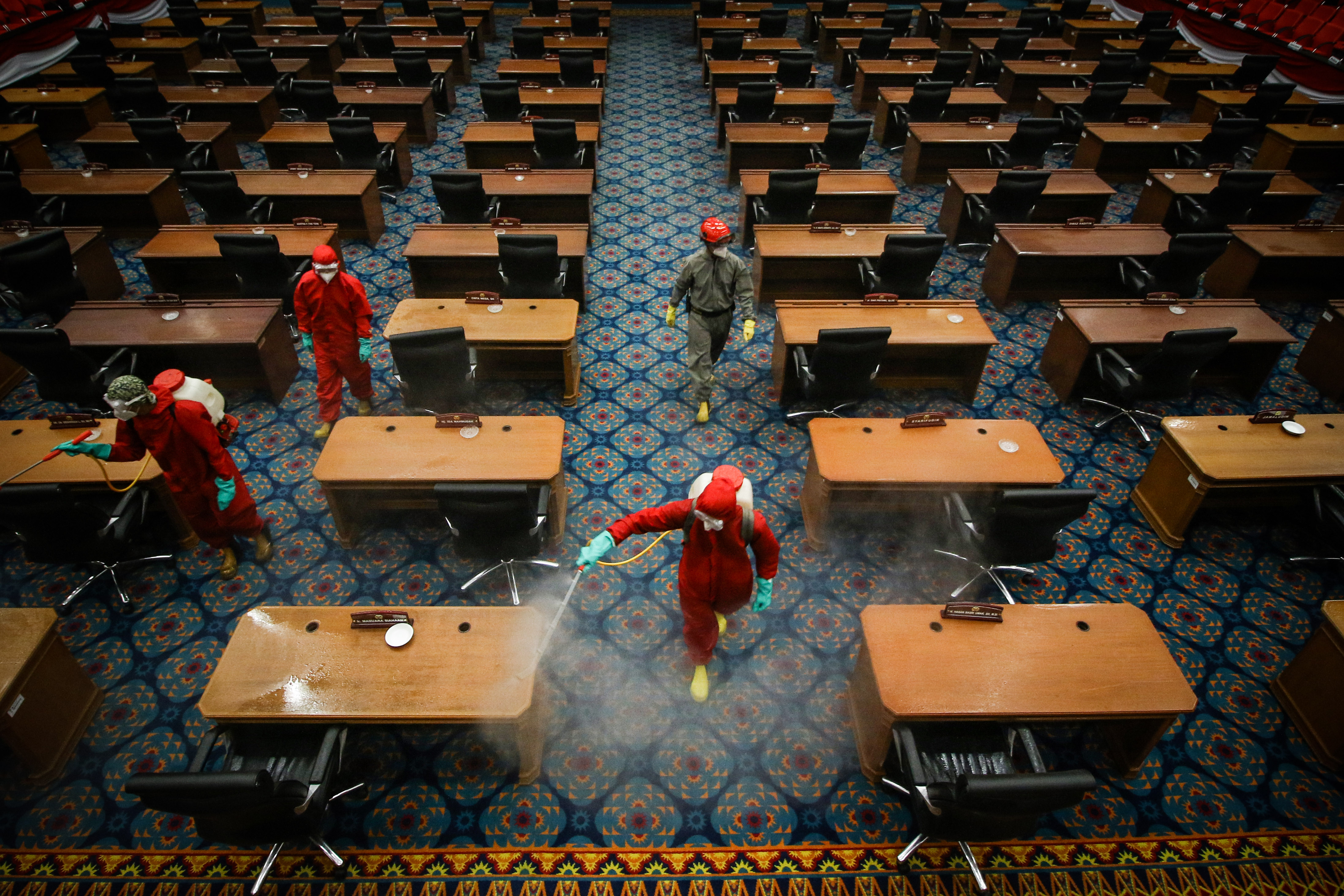 Petugas menyemprotkan cairan disinfektan di ruang sidang paripurna DPRD DKI Jakarta