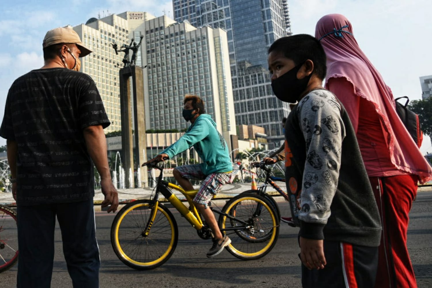 Kerumunan warga bersepeda di kawasan Bundaran HI dengan memakai masker