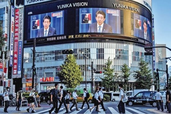 Layar besar di pusat kota menampilkan Perdana Menteri Jepang Shinzo Abe, 65, saat memberikan keterangan pers di Tokyo, Jepang, kemarin.