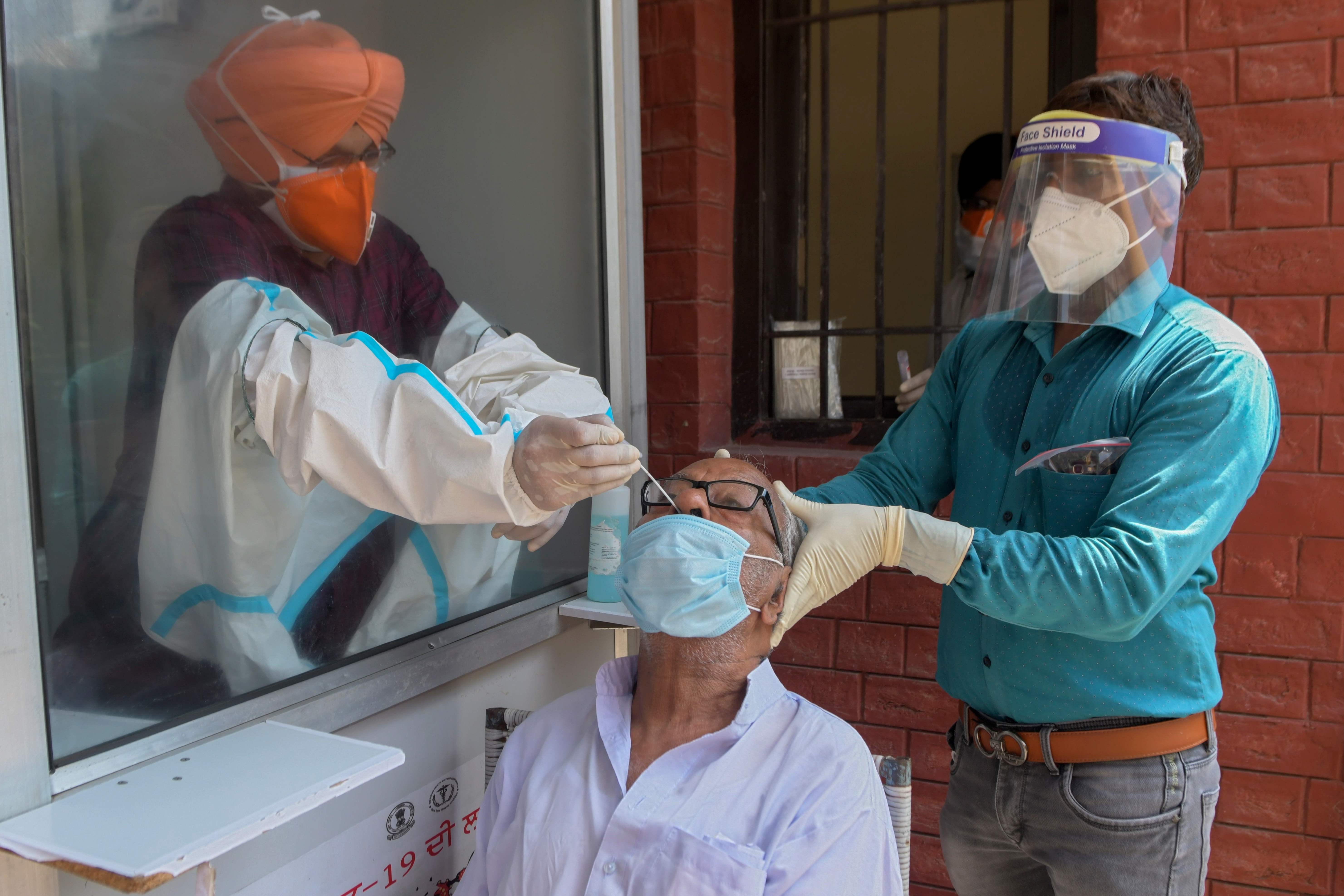 Pejabat kesehatan mengumpulkan sampel usap hidung dari seorang pria untuk menguji virus corona COVID-19, di rumah sakit sipil di Amritsar 
