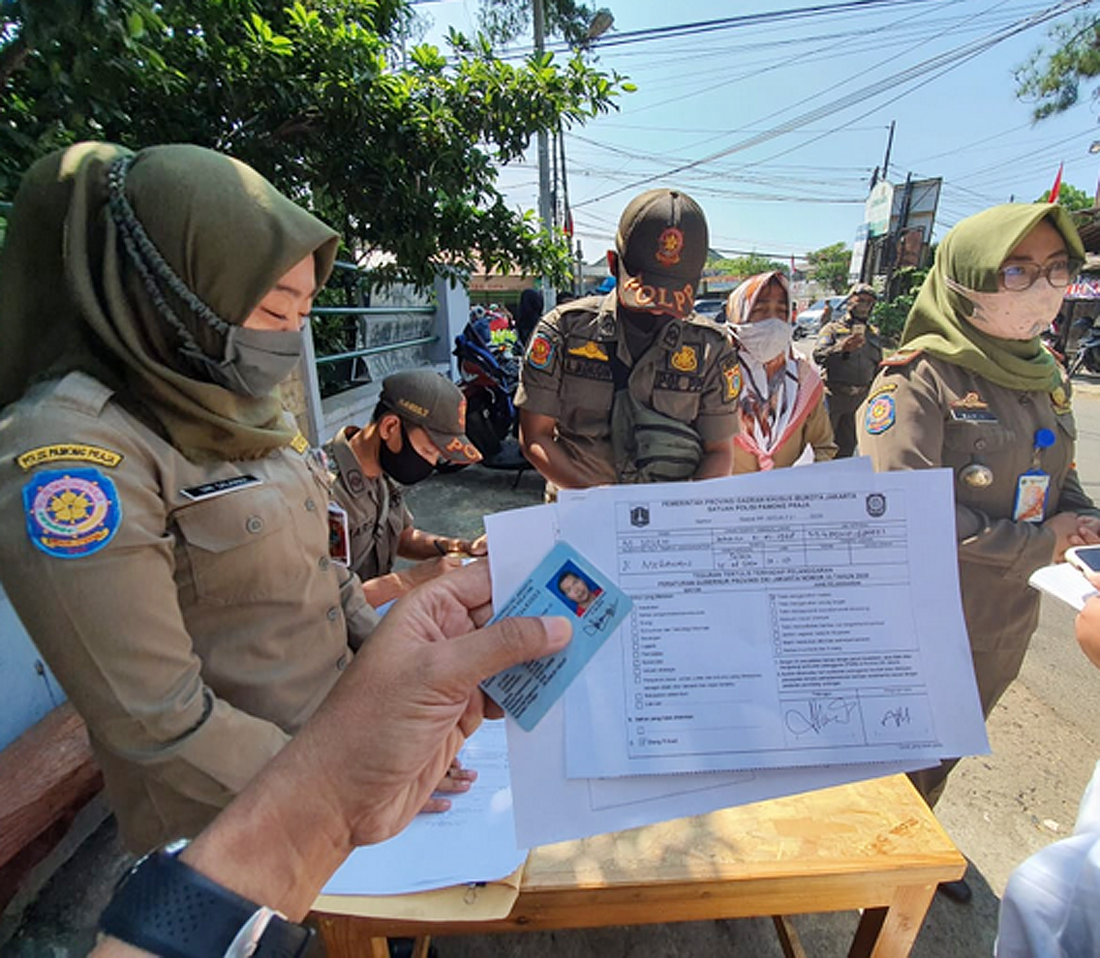 Warga menunjukkan denda administrasi yang harus dibayarkan Rp250 ribu saat terjaring razia masker di Cilandak, Jakarta.