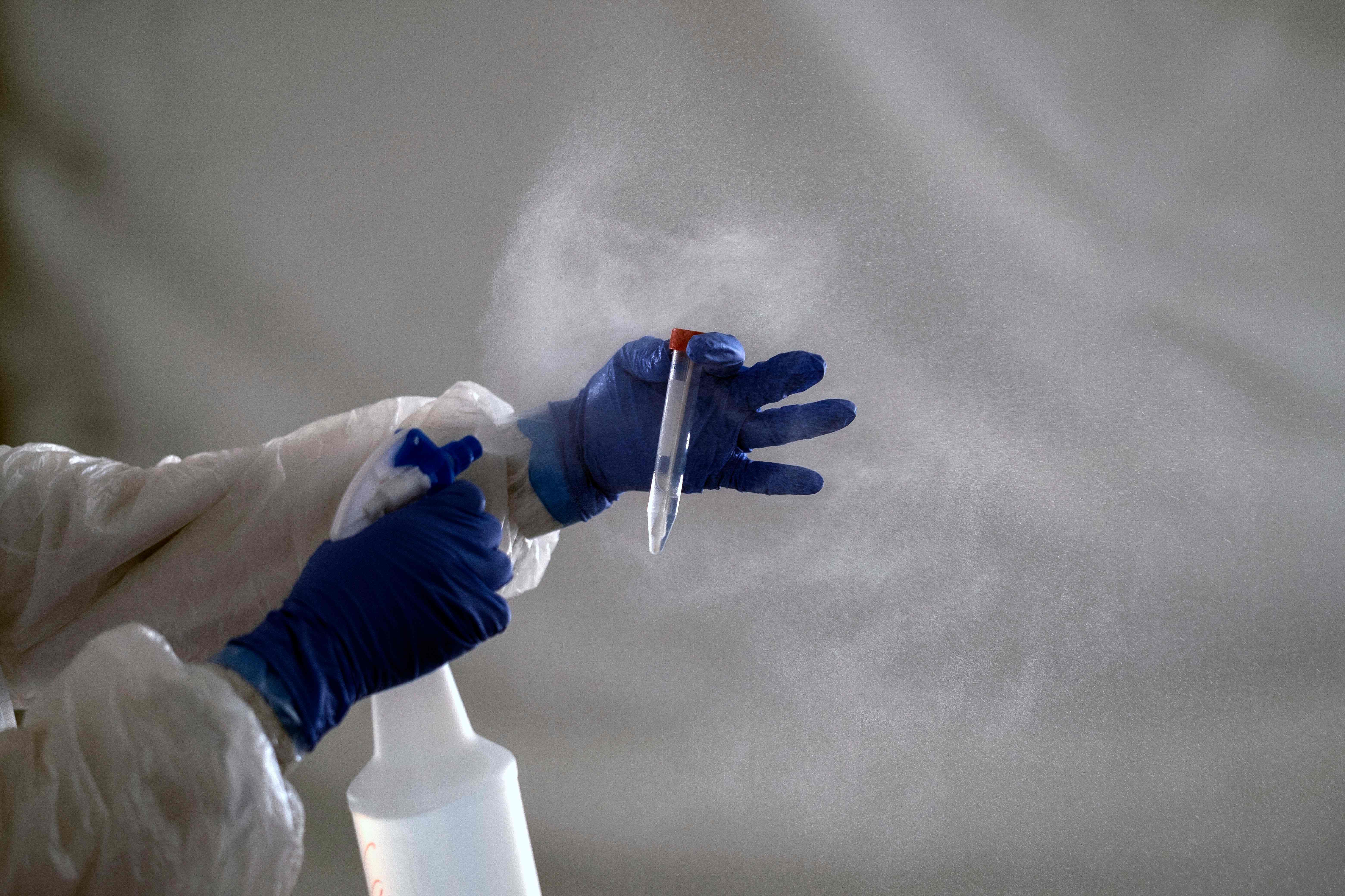 Ilustrasi pekerja laboratorum yang membersihkan tabung sampel covid-19.