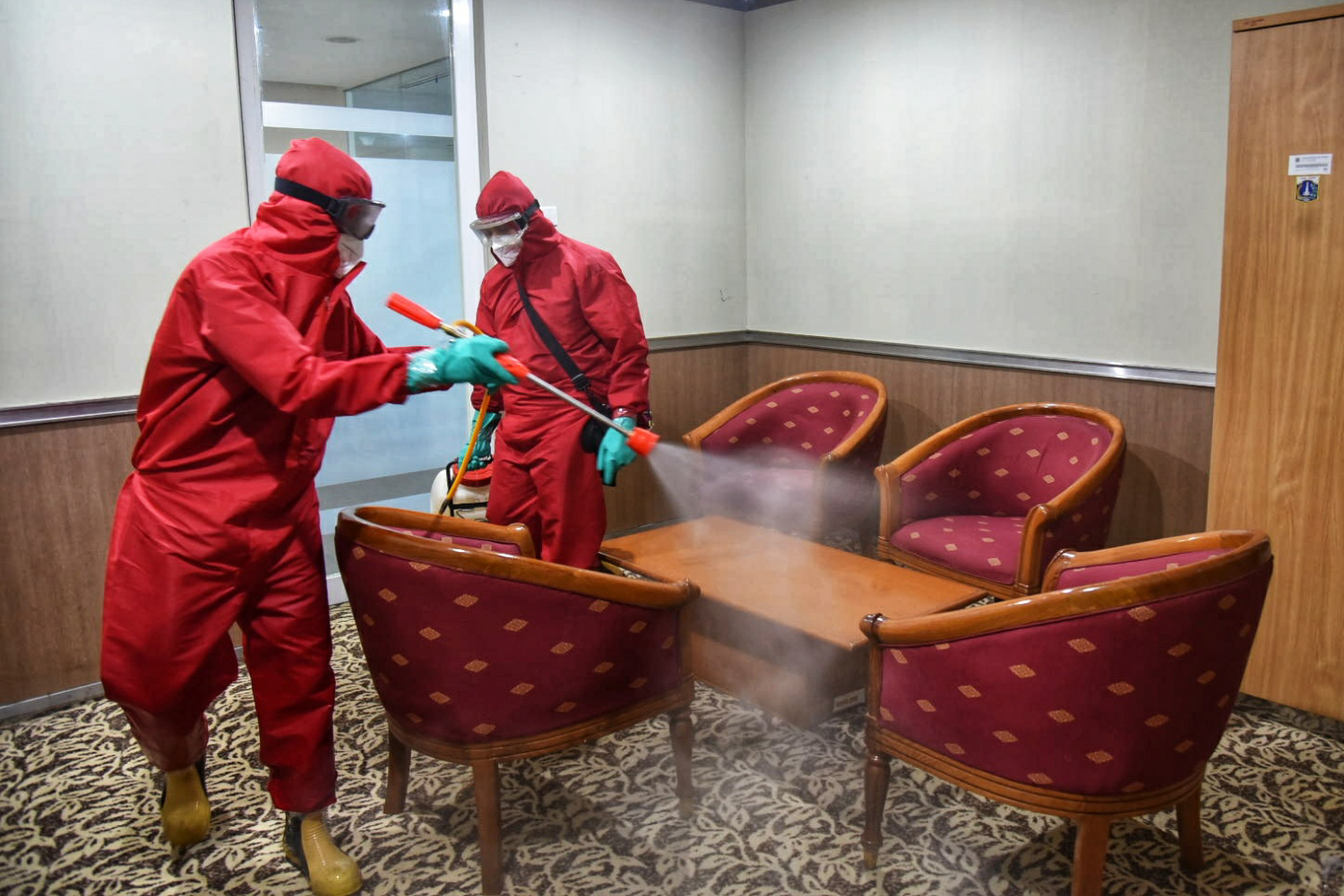 Petugas tengan menyemprotkan cairan disinfektan di area Gedung DPRD DKI Jakarta.