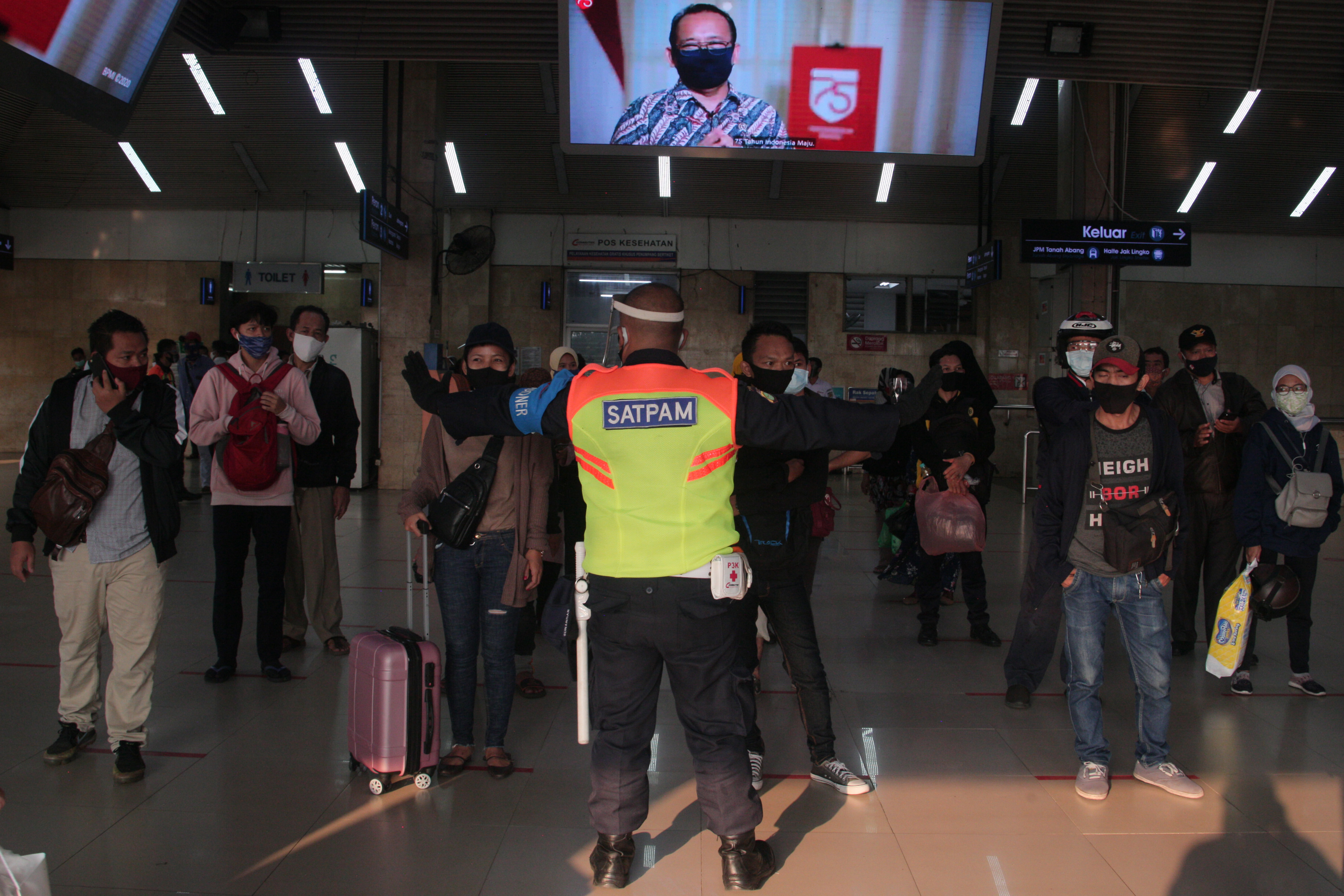 Petugas mengarahakan penumpang KRL untuk menjaga jarak ketika antre di dalam Stasiun Tanah Abang, Senin (10/8/2020) sore