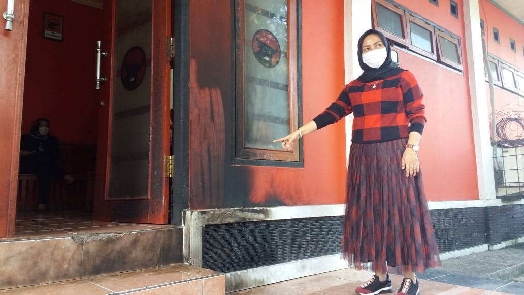 Ketua DPC PDI Perjuangan Kabupaten Cianjur, Susilawati menunjukkan hangus di pintu kantor akibat lemparan bom molotov, Jumat (7/8/2020)