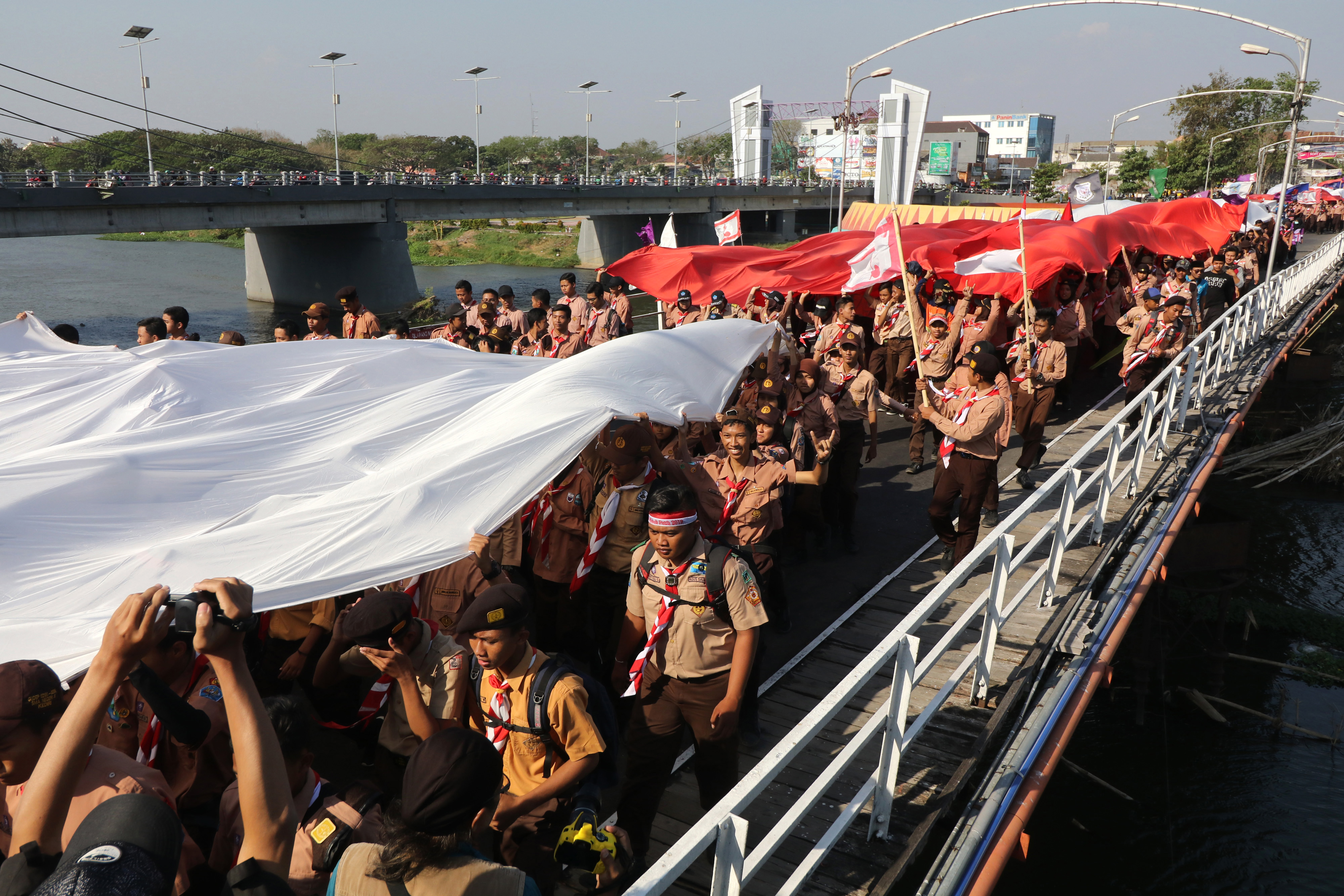 Sejumlah pemuda dan pemudi mengarak kain warna merah dan putih melewati jembatan lama sungai Brantas, Kota Kediri, Jawa Timur, Jumat (16/8/2