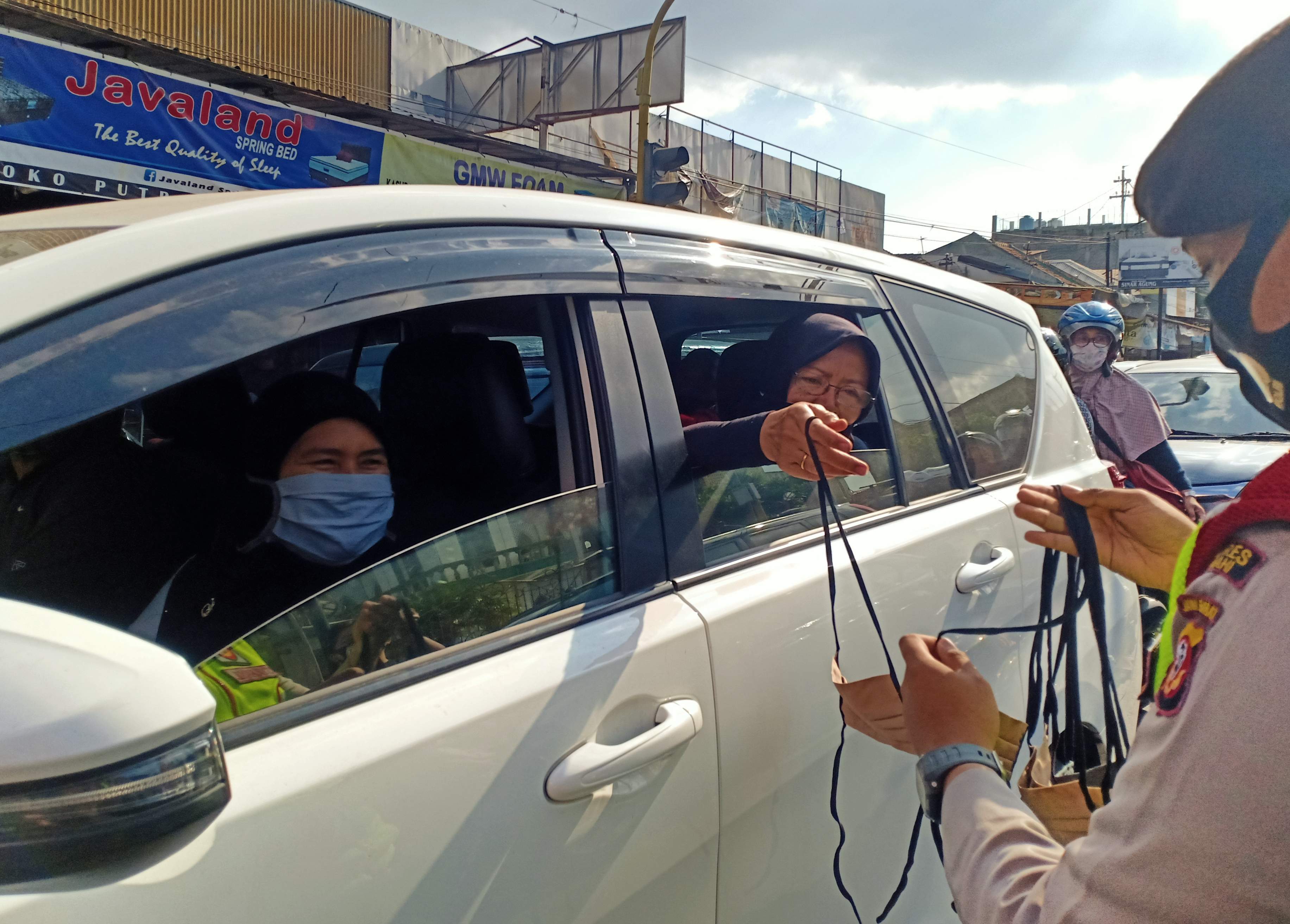 Anggota polisi memberikan masker kepada pengguna kendaraan yang melintas di wilayah Lembang, Kabupaten Bandung Barat, Minggu (2/8).