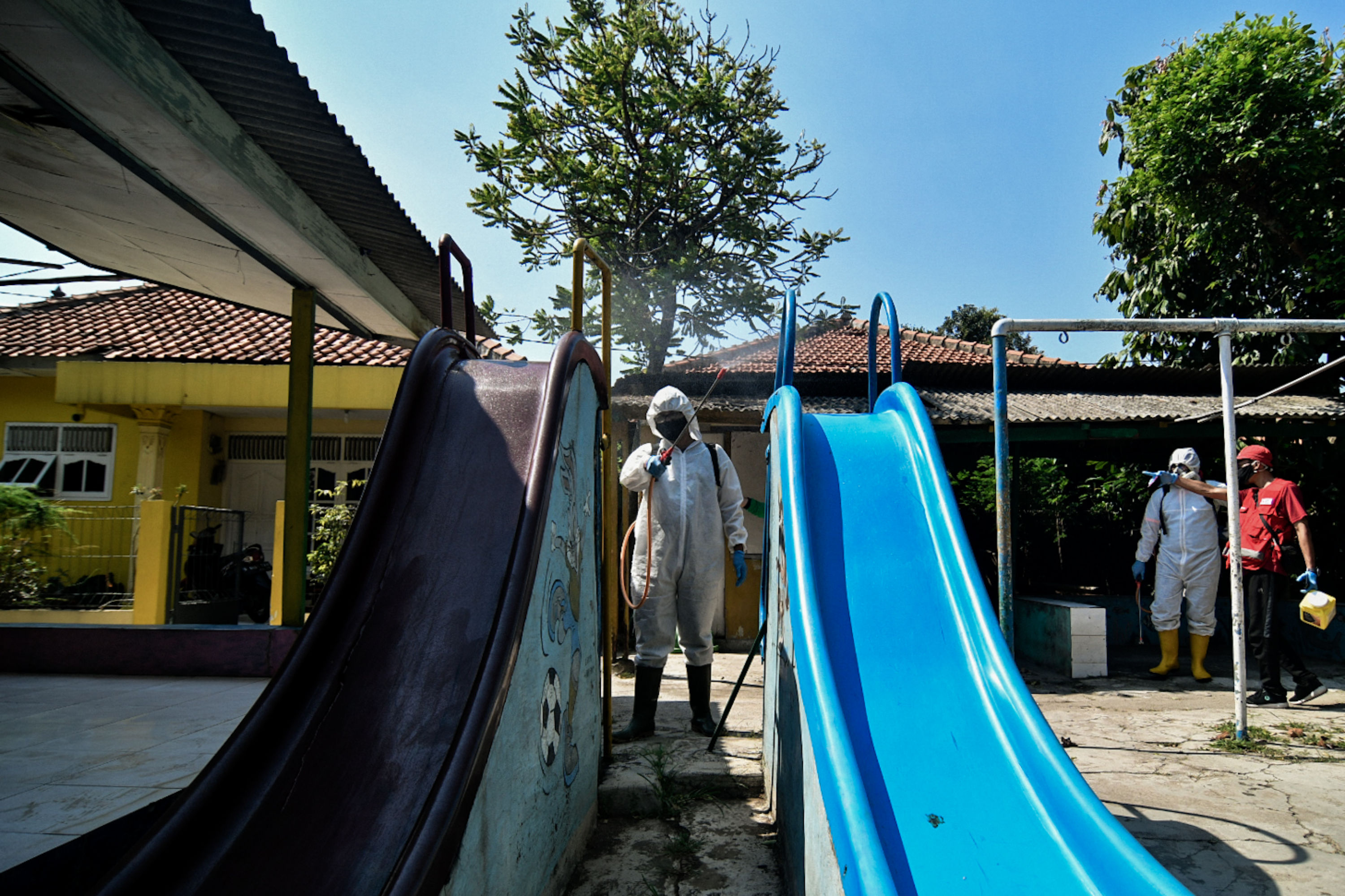 Petugas Palang Merah Indonesia menyemprotkan disinfektan di kawasan permukiman, Kramat Jati, Jakarta