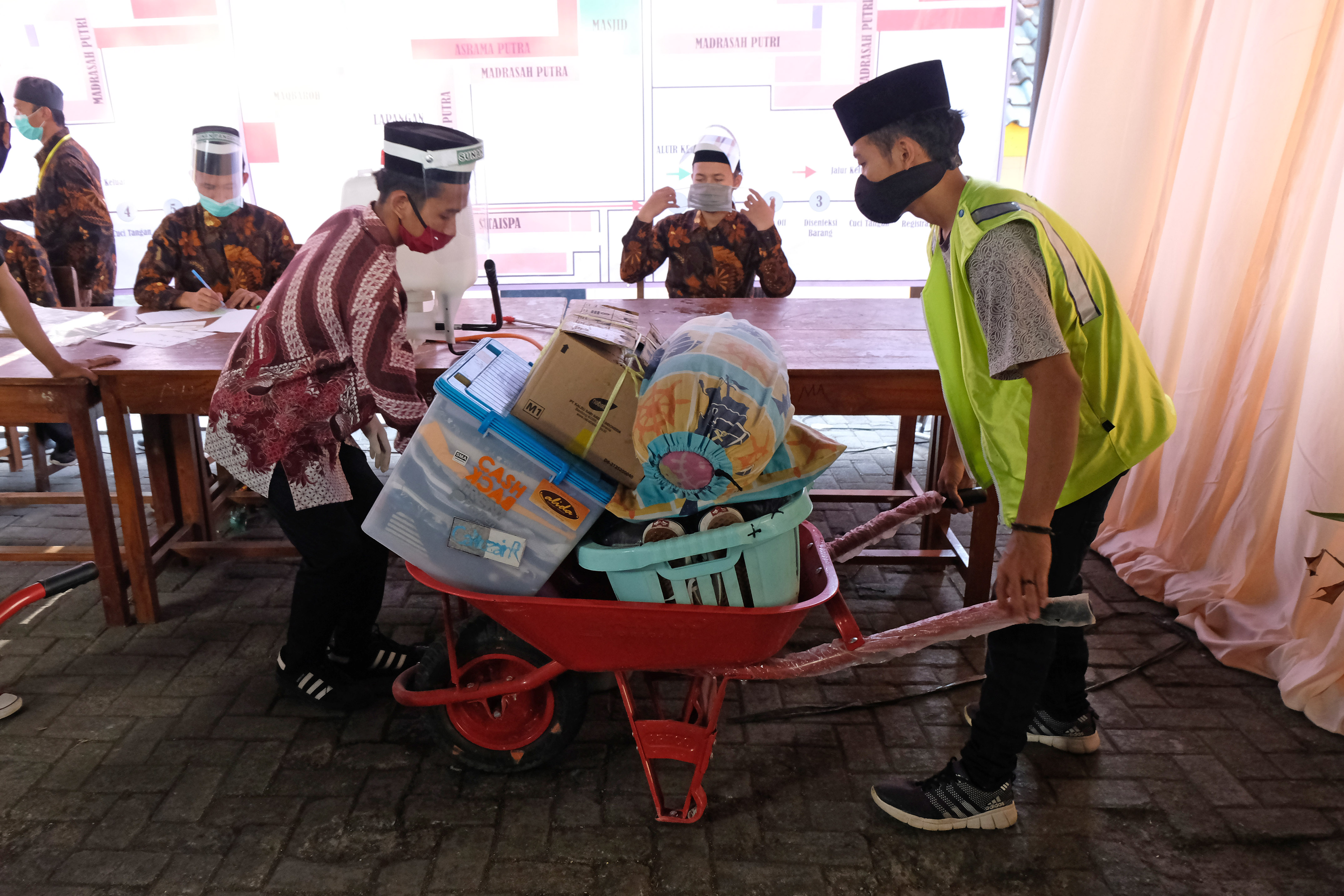 Sejumlah petugas mengangkut barang bawaan santri saat kedatangan kembali di kompleks Pondok Pesantren Sunan Pandanaran Ngaglik, Sleman.