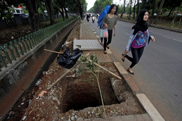 Ilustrasi -- Pejalan kaki berjalan di trotoar yang rusak di Jakarta Selatan