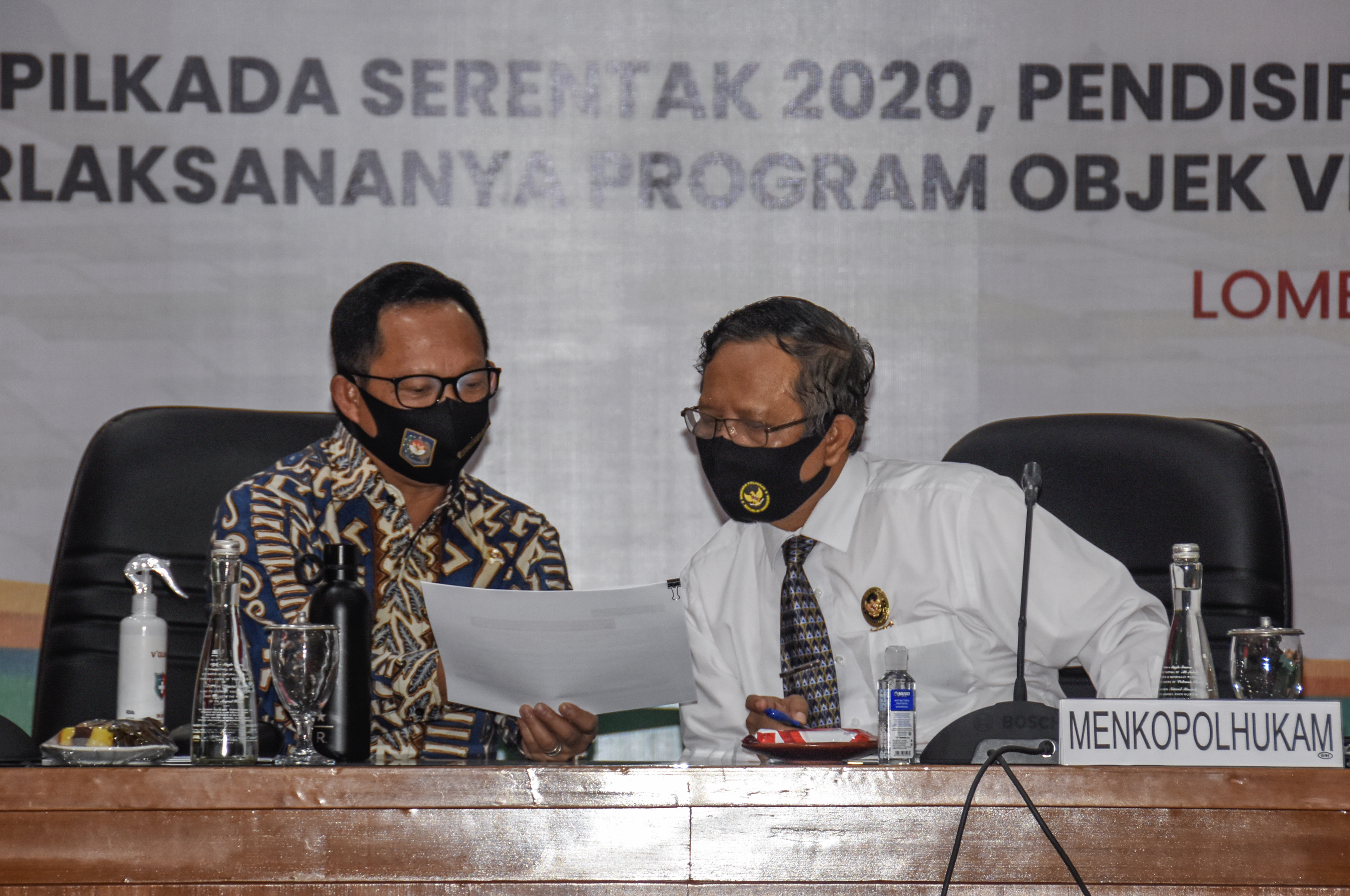 Menteri Dalam Negeri Tito Karnavian (kiri) berbincang bersama Menko Polhukam Mahfud MD (kanan)