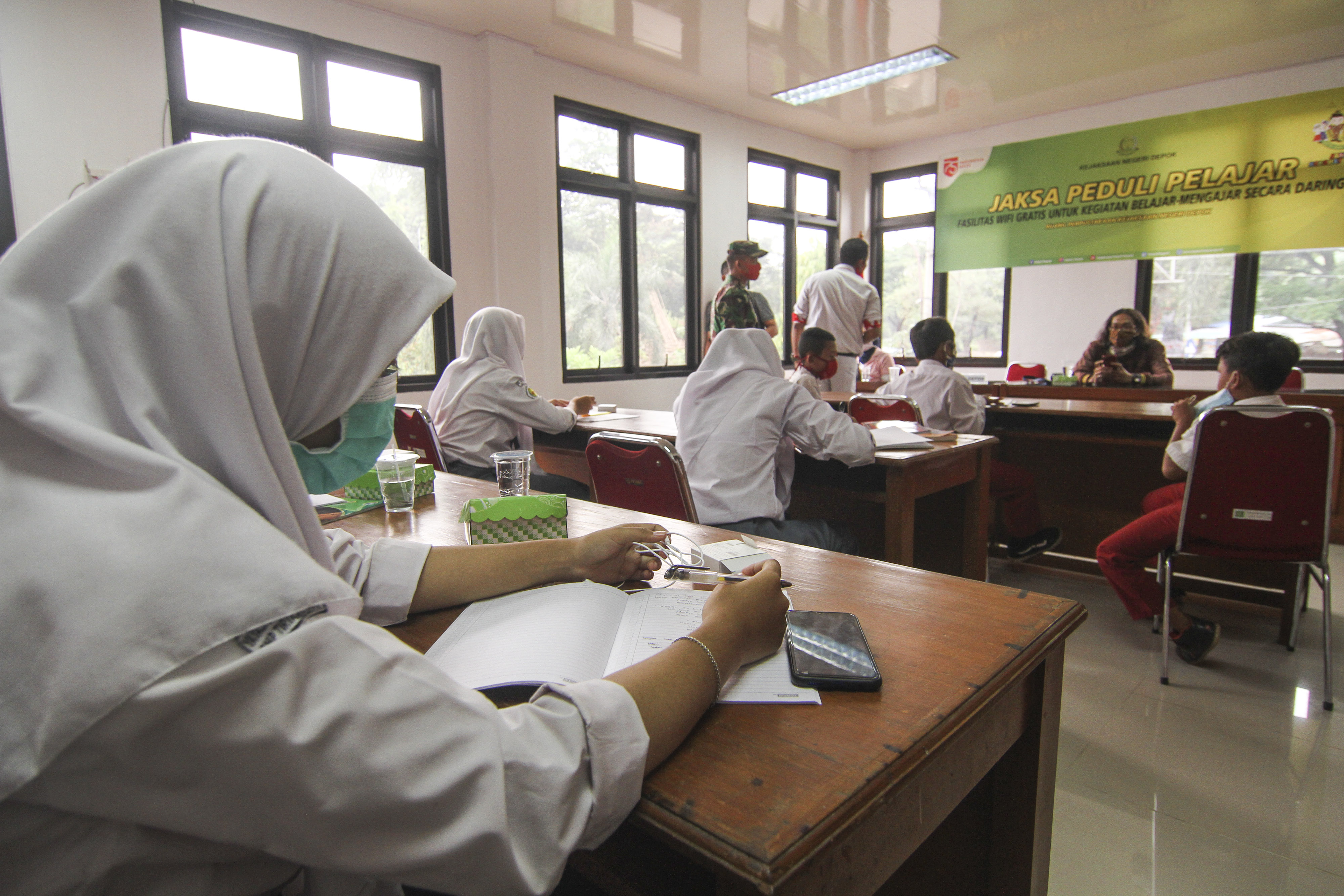 Sejumlah pelajar menggunakan wifi gratis di perpustakaan Kejaksaan Negeri Kota Depok, Jawa Barat, Selasa (18/8/2020).