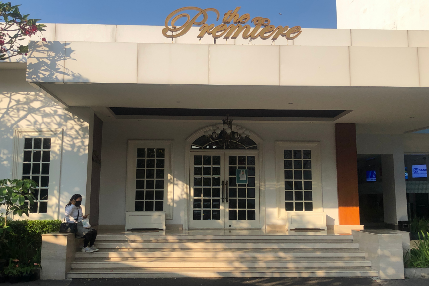 Seorang warga duduk di depan The Premiere Metropole XXI Megaria di Jakarta Pusat yang masih tutup.