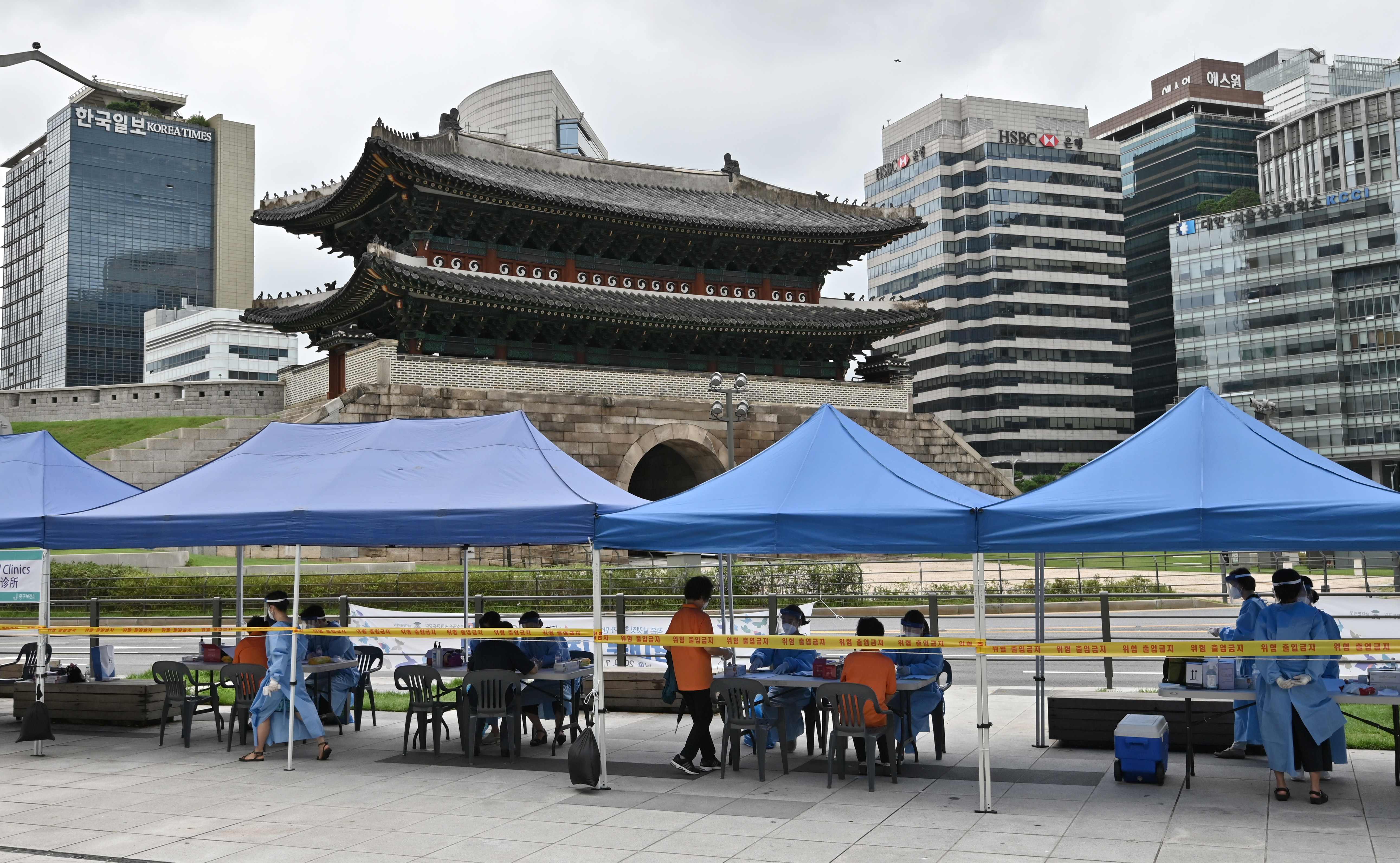 Petugas menanti warga yang akan menjalani tes covid-19 di dekat Namdaemun, gerbang berusia 600 tahun (warisan budaya nasional Korsel)