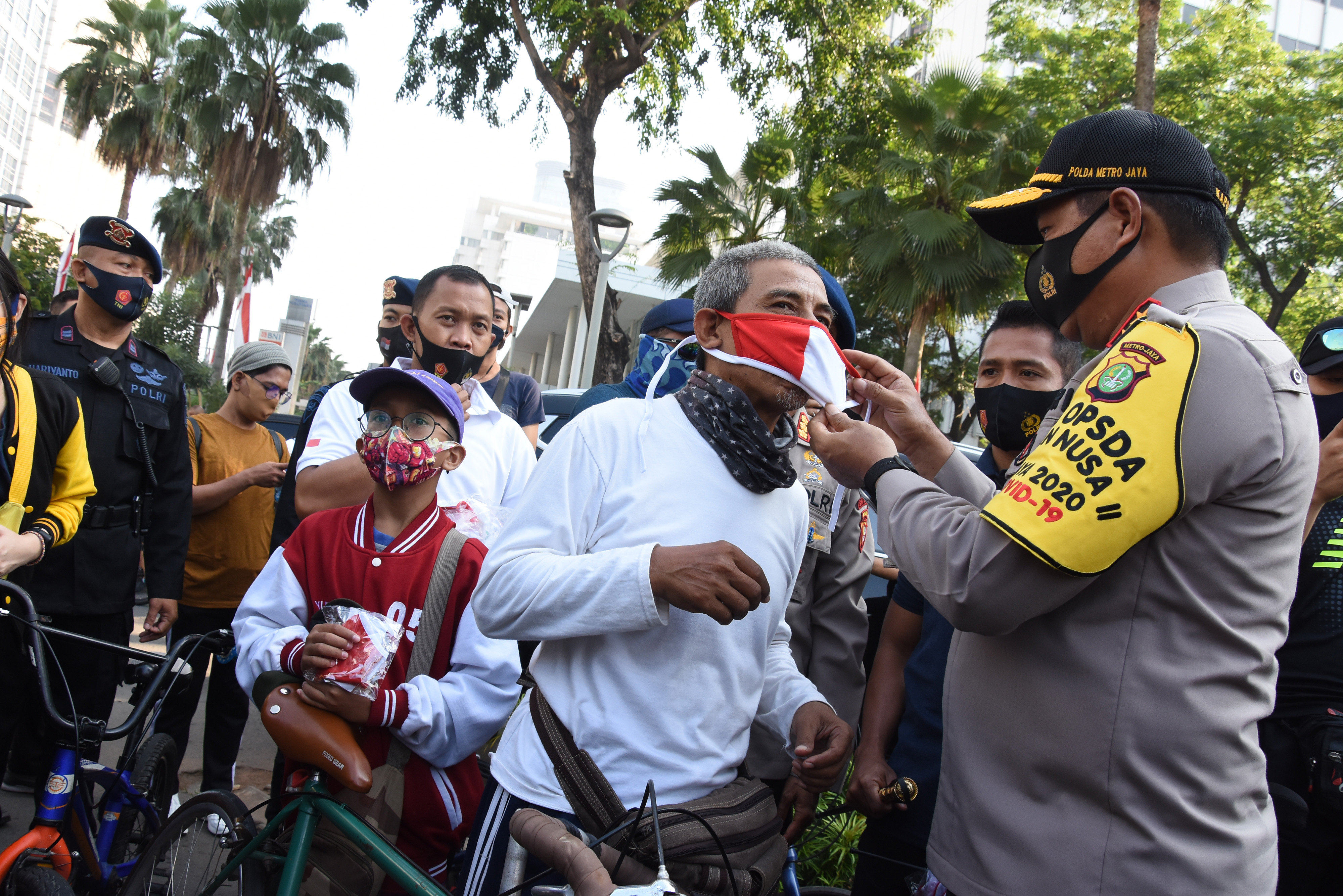 Kapolda Metro Jaya Irjen Pol Nana Sudjana (kanan) memasangkan masker kepada warga yang sedang berolahraga di kawasan Bundaran HI, Jakarta.