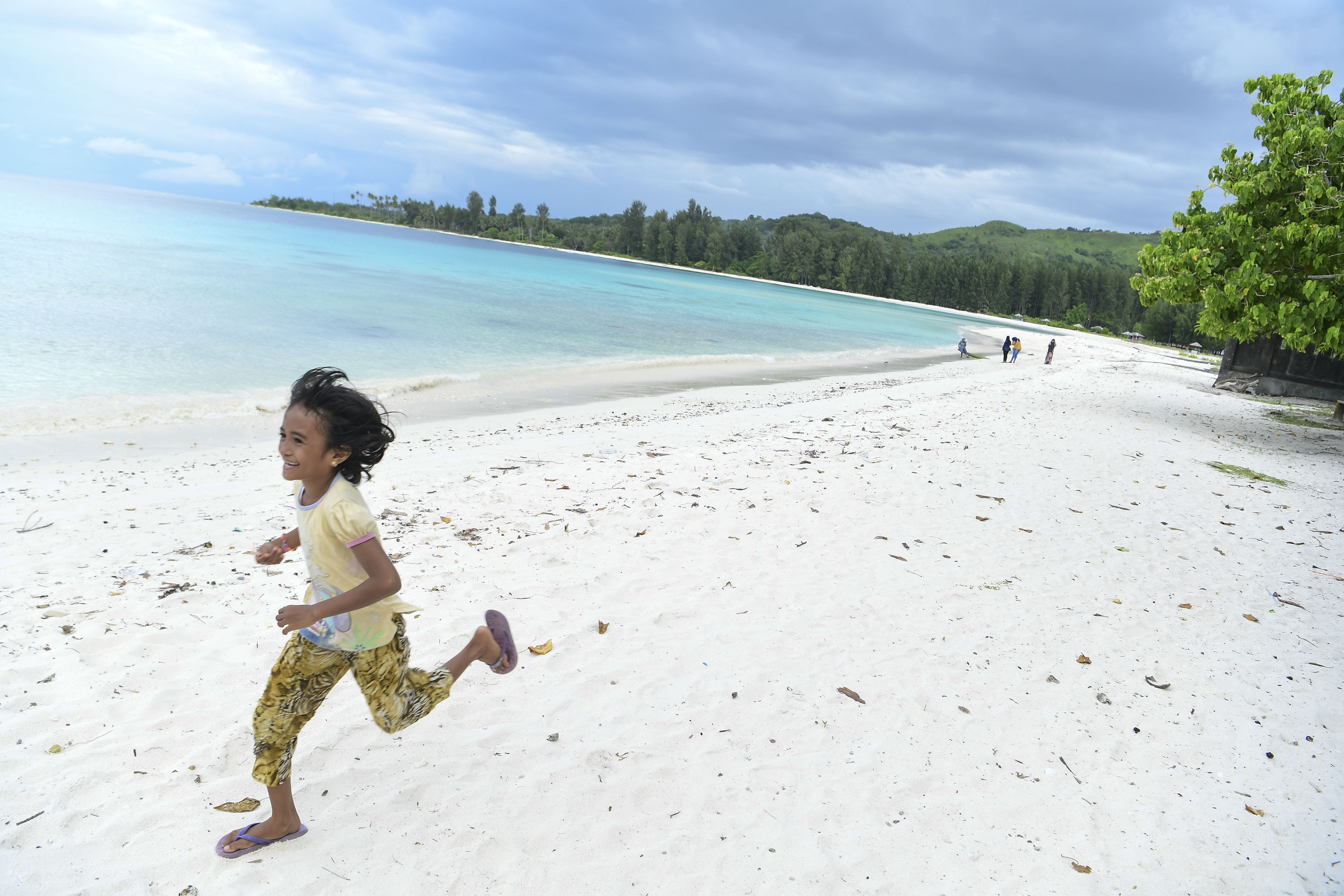 Seorang anak berlari di tengah keindahan Pantai Jikumerasa, Maluku.