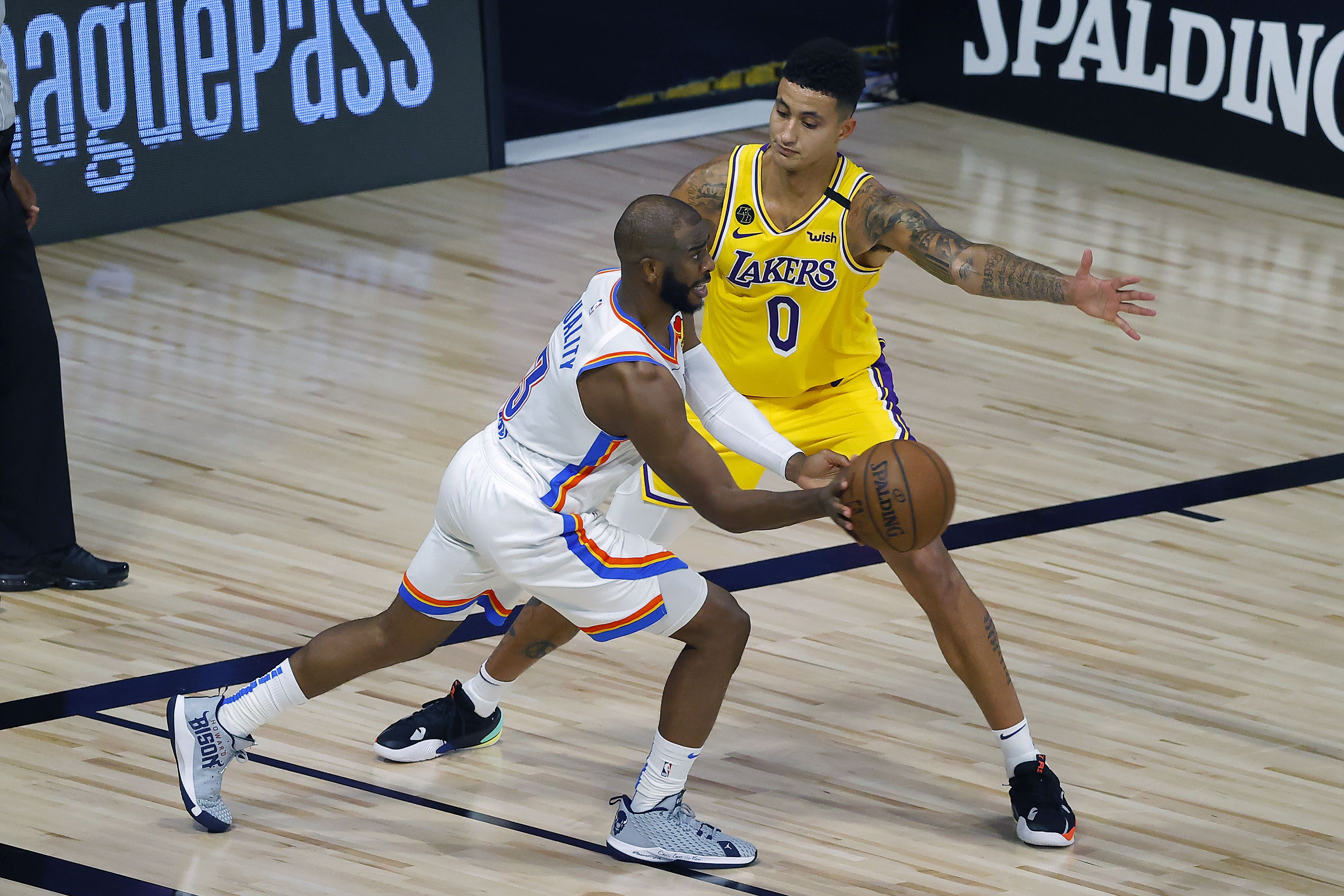 Kyle Kuzma (kanan) dari Los Angeles Lakers berusaha menghadang Chris Paul (kiri) dari Oklahoma City pada laga di Lake Buena Vista, Florida. 