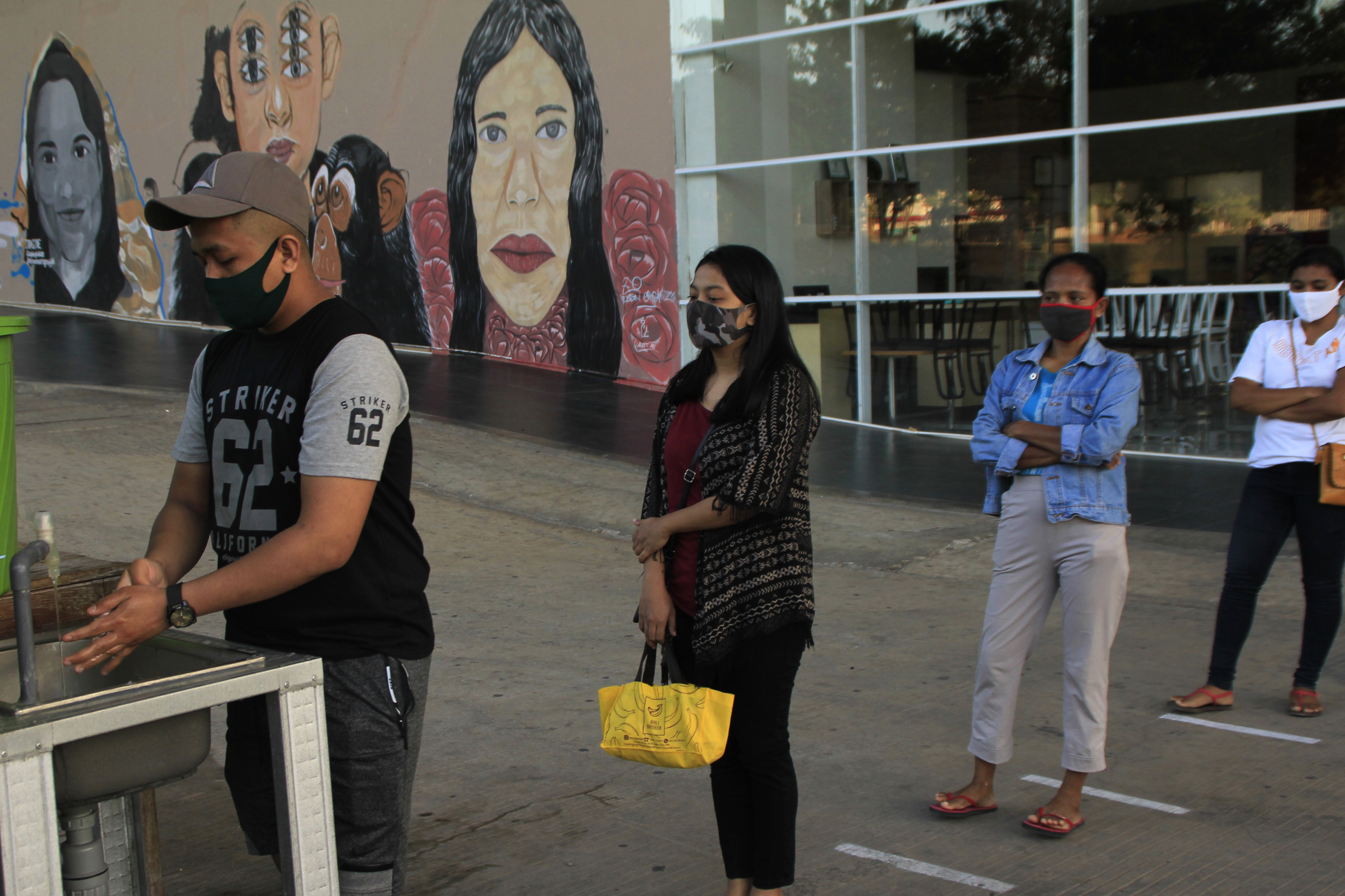 Pengunjung antre untuk mencuci tangan saat berada di halaman salah satu pusat perbelanjaan di Kota Kupang, NTT, Selasa (9/6/2020).