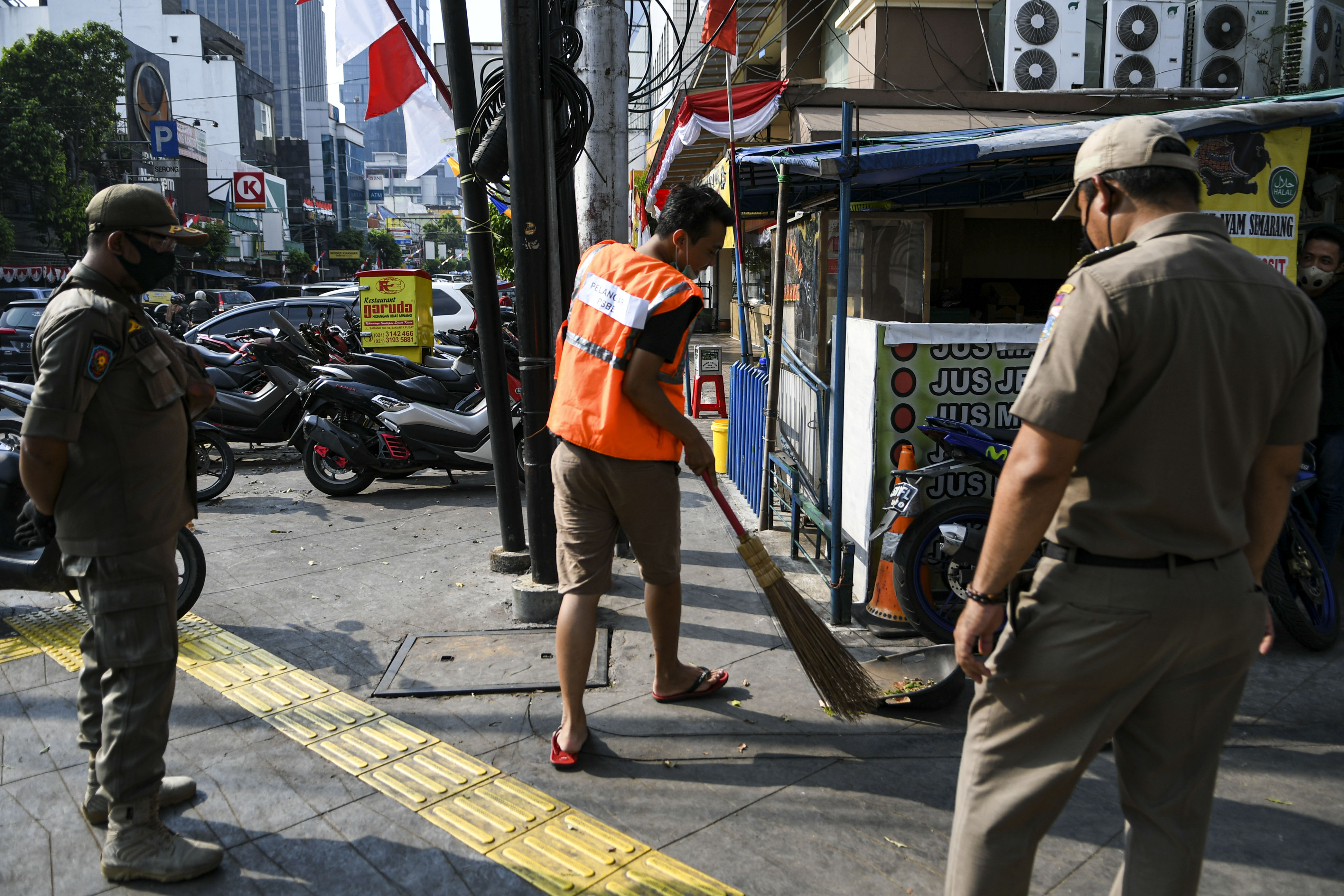 Petugas Satpol PP mengawasi pelanggar aturan pembatasan sosial berskala besar (PSBB) melaksanakan sanksi kerja sosial
